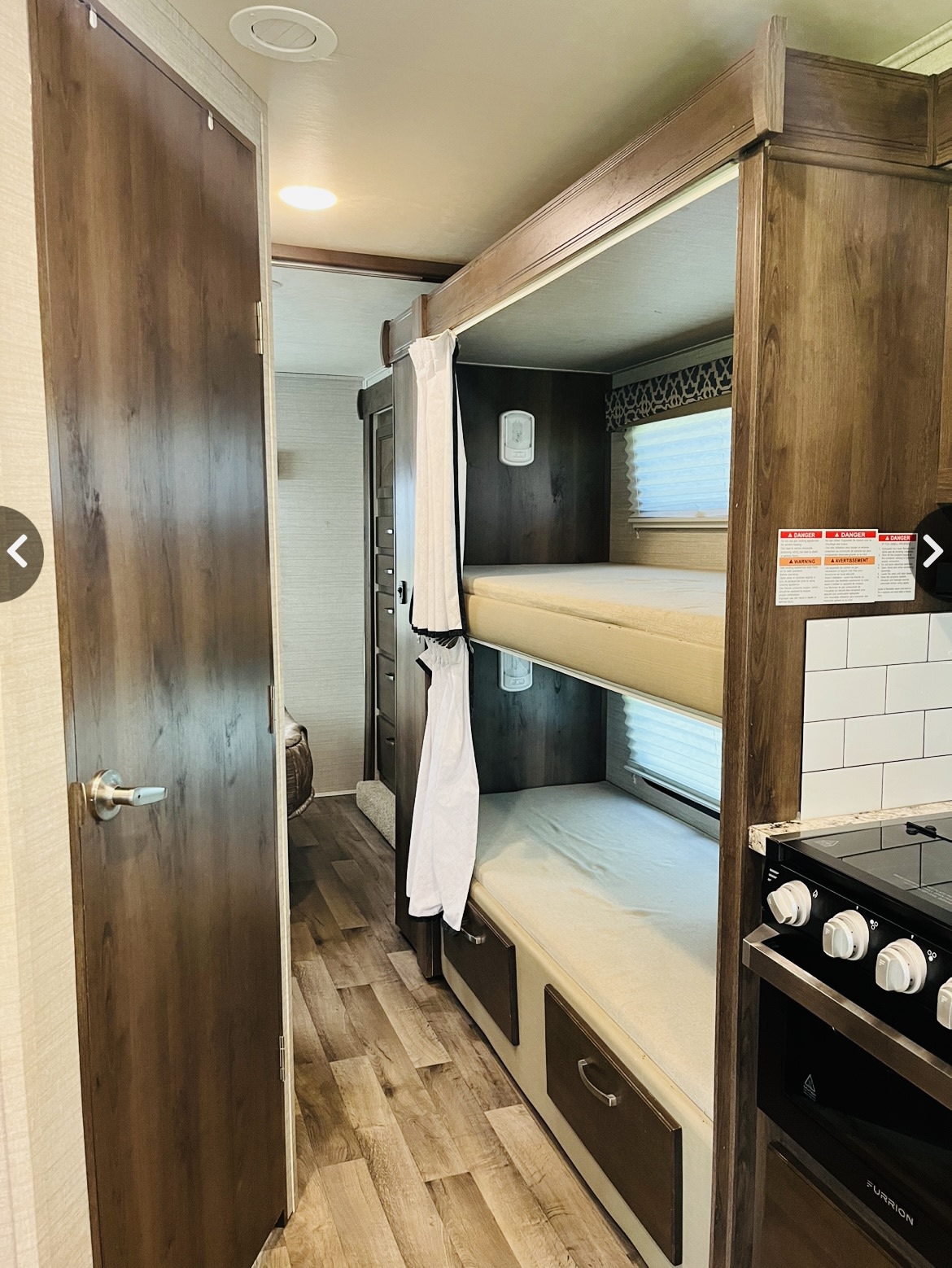 Inside this RV rental: cozy bunk beds with curtains, a compact kitchen, and a wide hallway. Perfect for family adventures.. Jayco Redhawk 2020