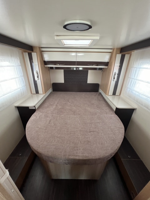 Cozy RV rental bedroom features a comfy bed, overhead storage, side tables, windows, and skylight. Ideal for trips!. McLOUIS PEUGEOT 279 2024