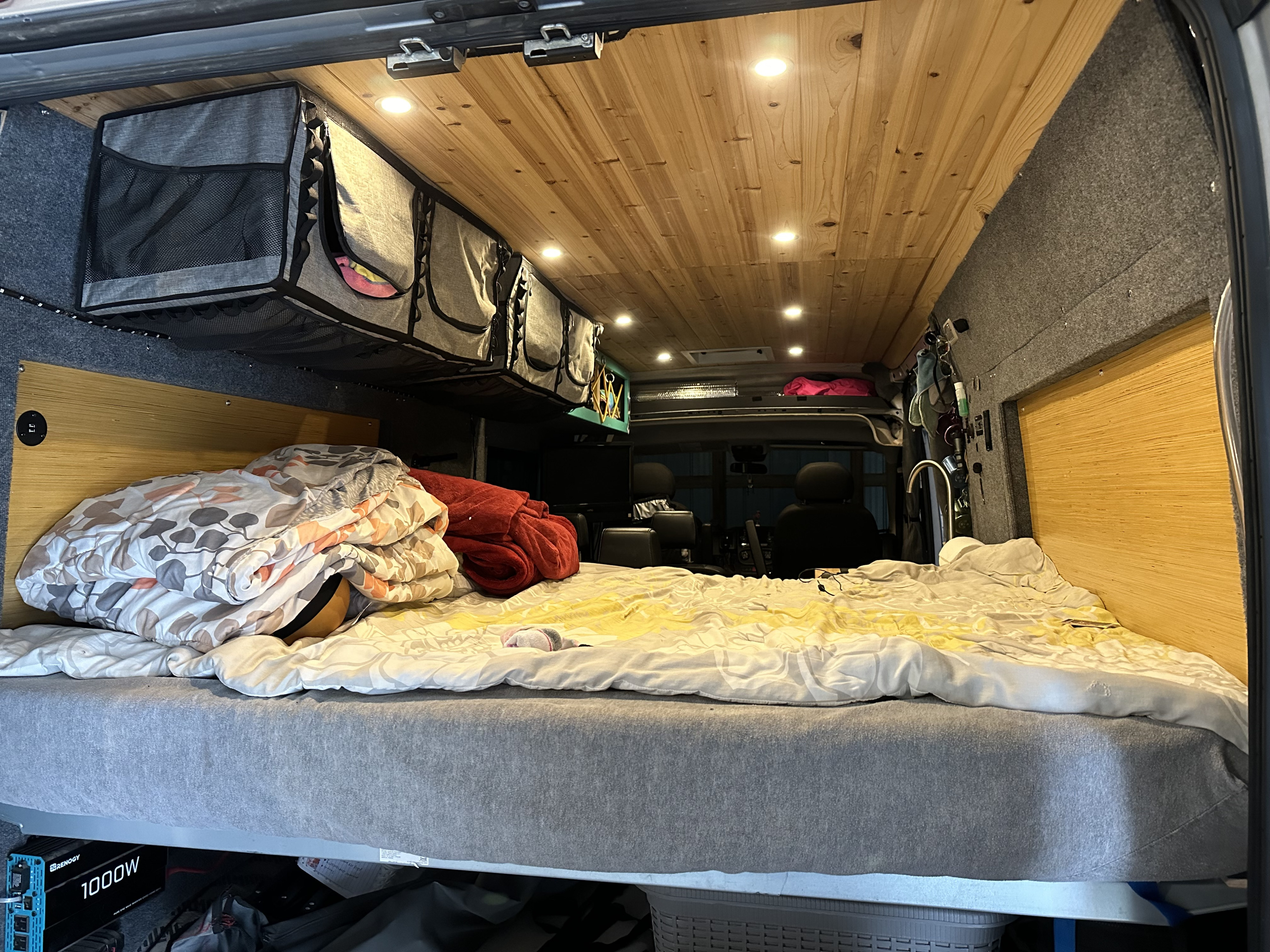 This rv rental offers a comfortable van interior with a bed, overhead storage, wooden ceiling, and ambient lighting.. Dodge Promaster 2014