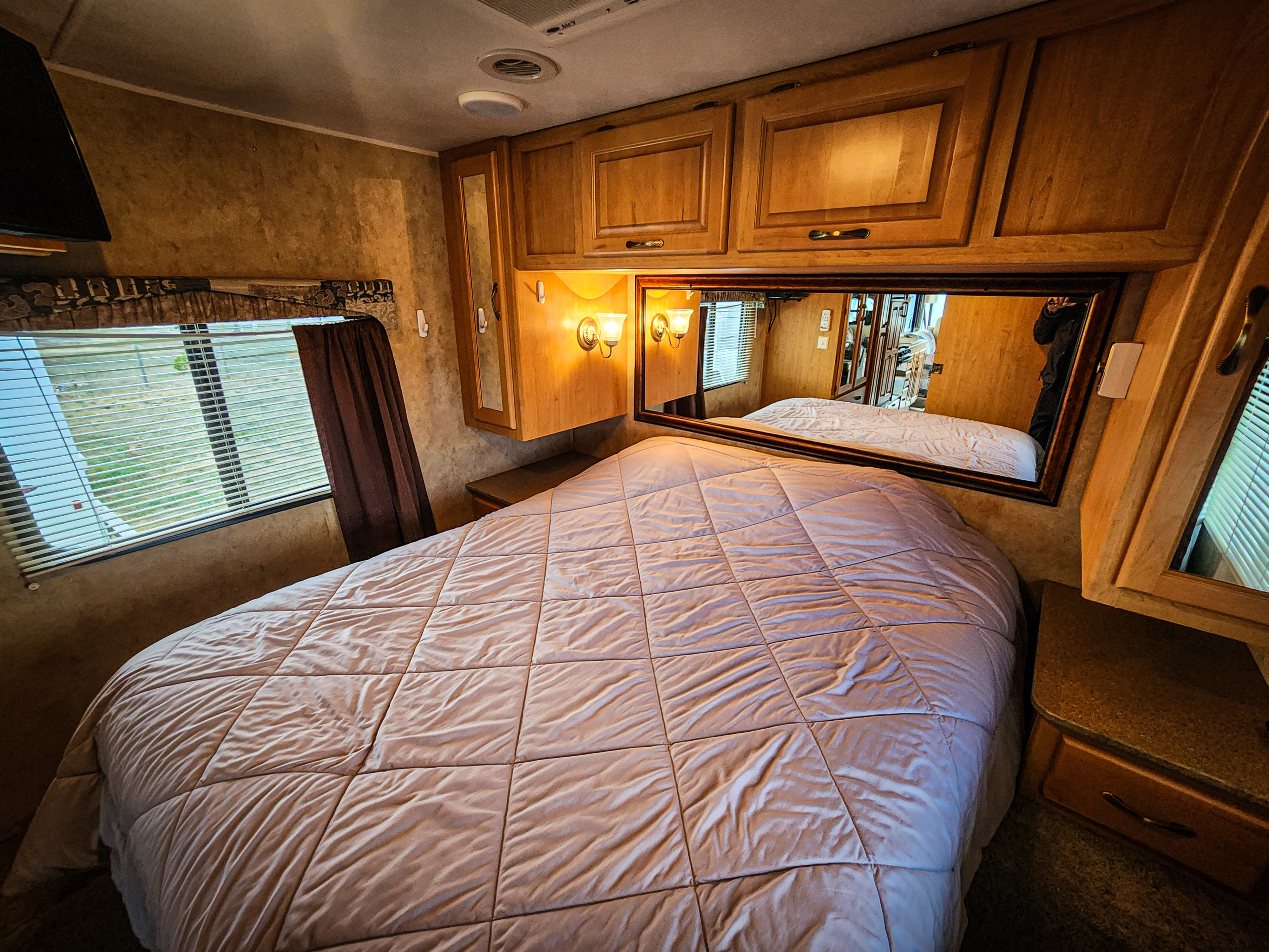 Explore this inviting RV rental bedroom with a comfy bed, built-in mirror, and ample storage.. Damon Corporation Daybreak 2007