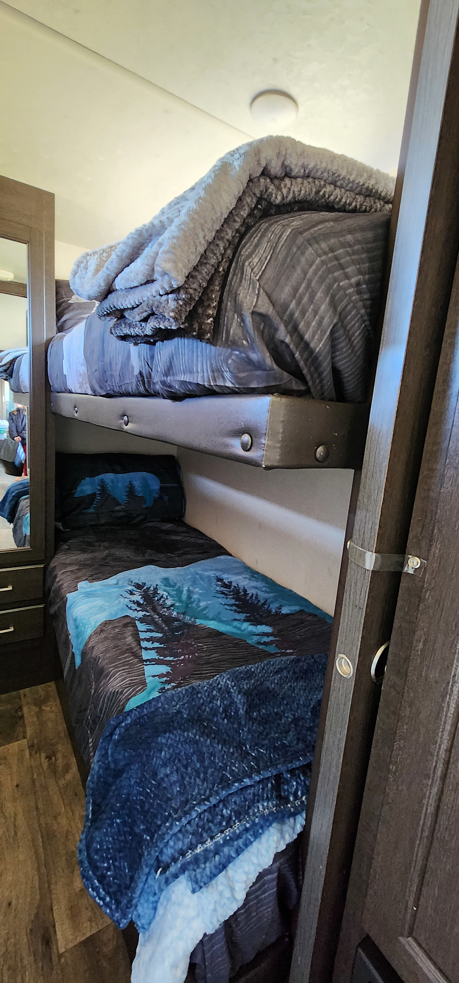 Cozy bunk beds in an RV rental, featuring nature-themed bedding (bear and trees). Ideal for compact family travel.. Forest River Wildwood X-Lite 2019