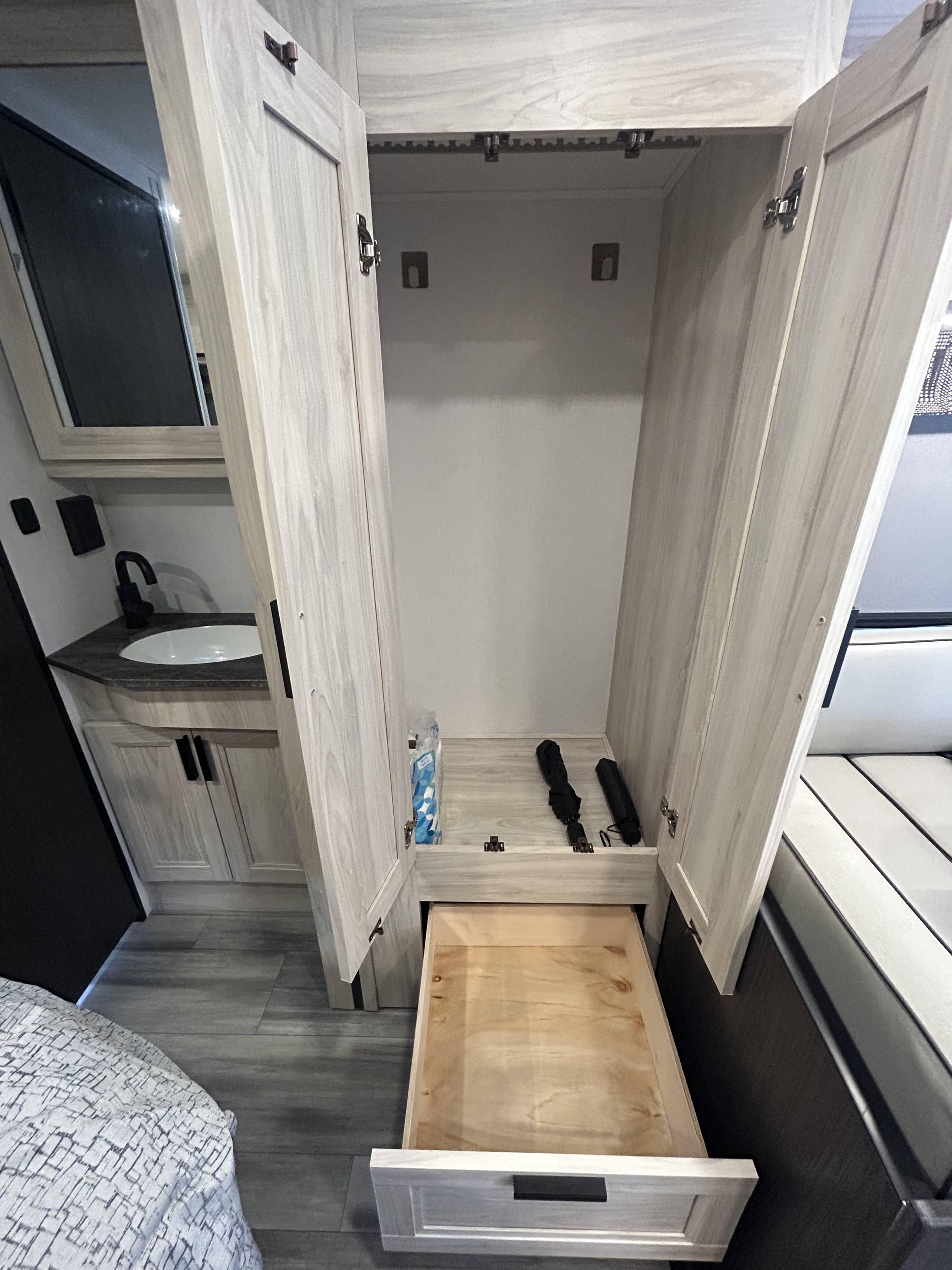 RV rental interior: an open wardrobe with a pull-out drawer and nearby sink vanity offers practical storage.. Forest River Sunseeker LE 2023