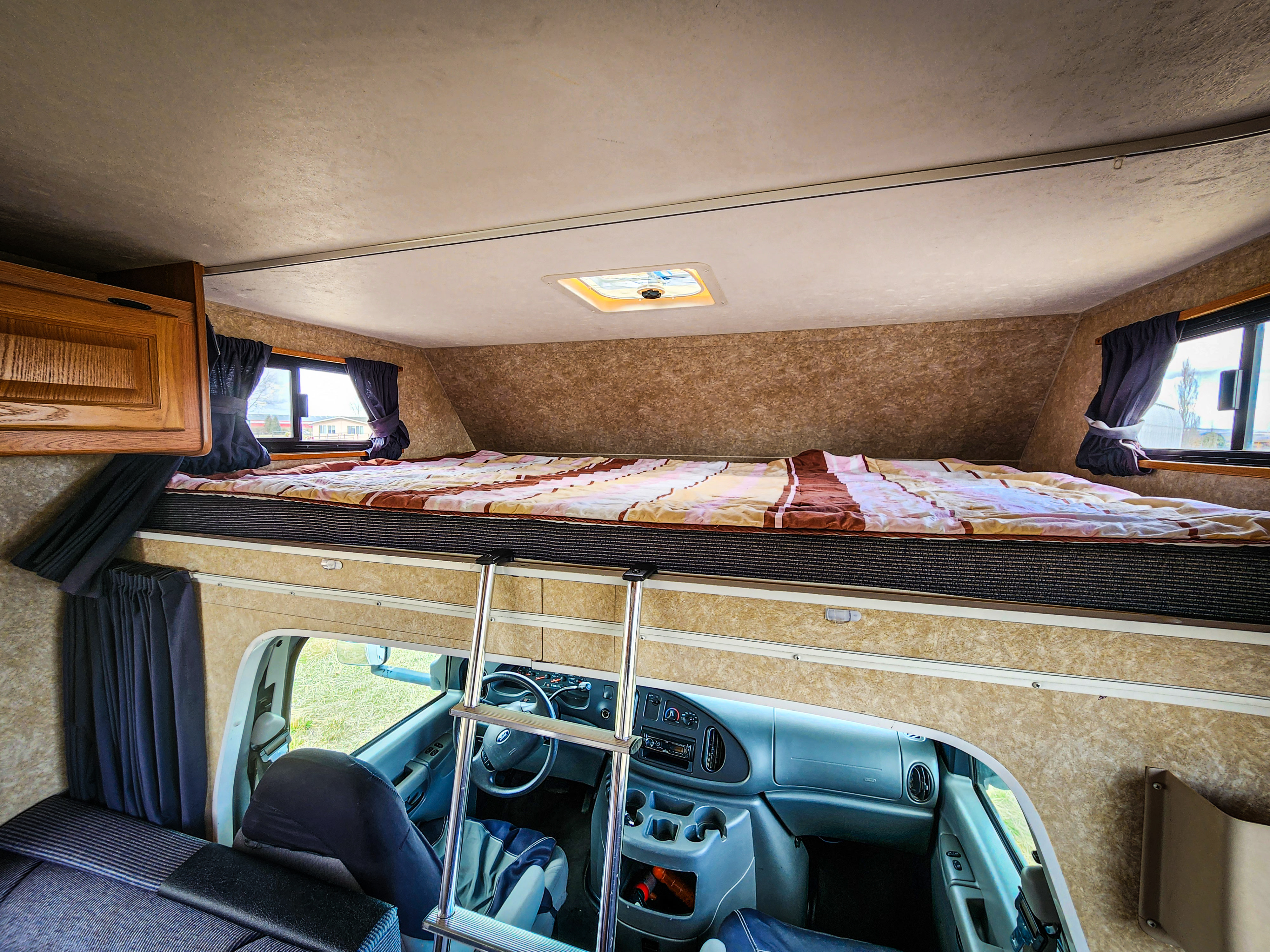 Cozy RV rental interior shows a large sleeping area above the driver's cockpit, accessed by a ladder.. Four Winds Majestic 2008