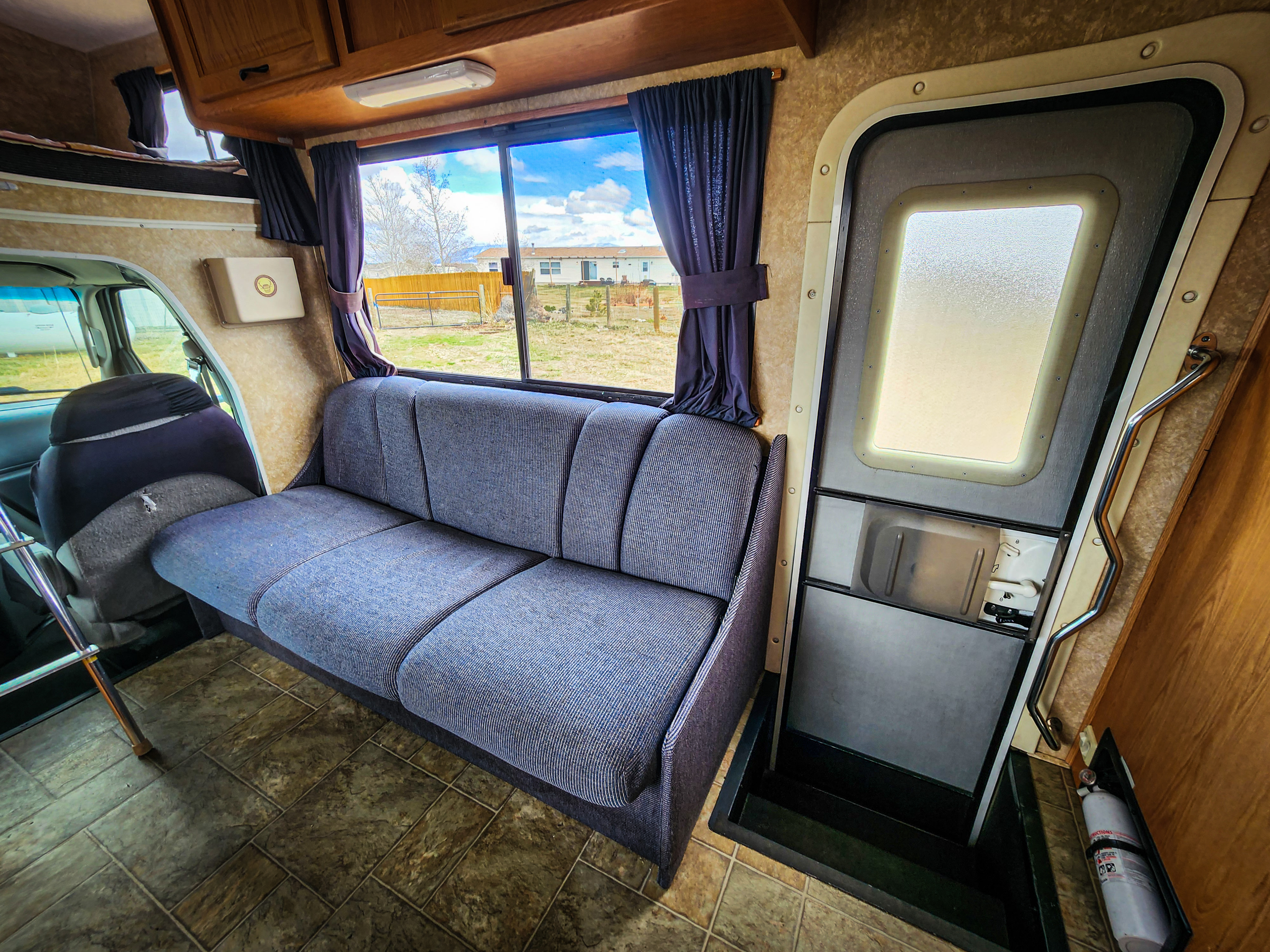 Step inside this cozy RV rental! Features a blue sofa, large window views, and a secure entrance door.. Four Winds Majestic 2008