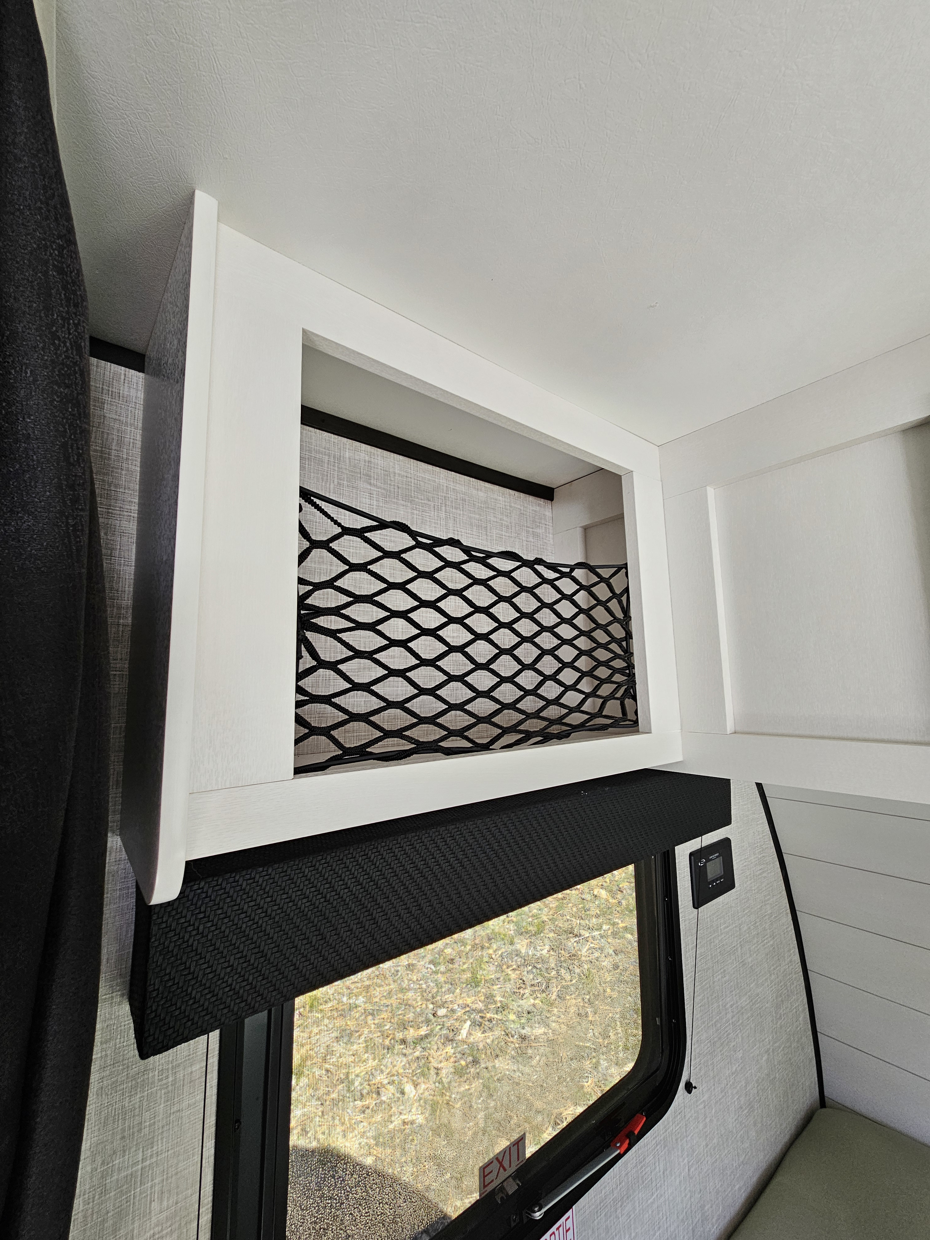 Overhead storage with mesh net, a window with a blackout blind, and a control panel in an RV rental interior.. Jayco JAY FLIGHT SLX 184BSW BAJA 2024