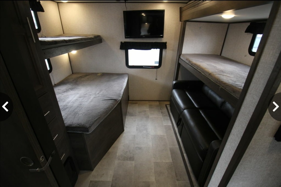 This RV rental features a compact interior with multiple bunk beds, a cozy sofa, and a wall-mounted TV, optimizing space.. Dutchmen Coleman Light 2020