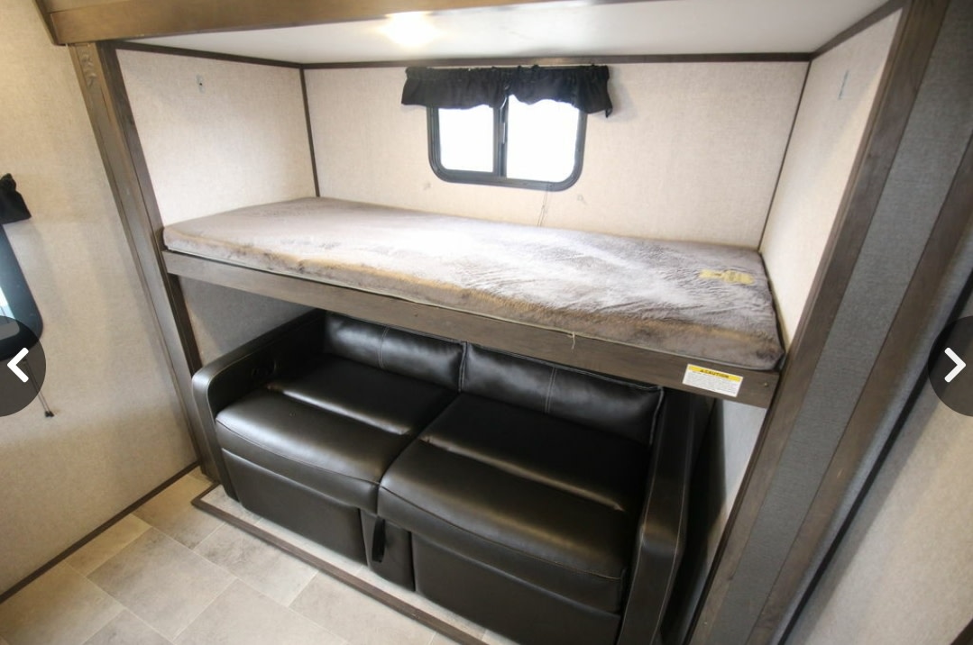 RV rental: Efficient design with a bunk bed above a black sofa, maximizing space for travelers.. Dutchmen Coleman Light 2020