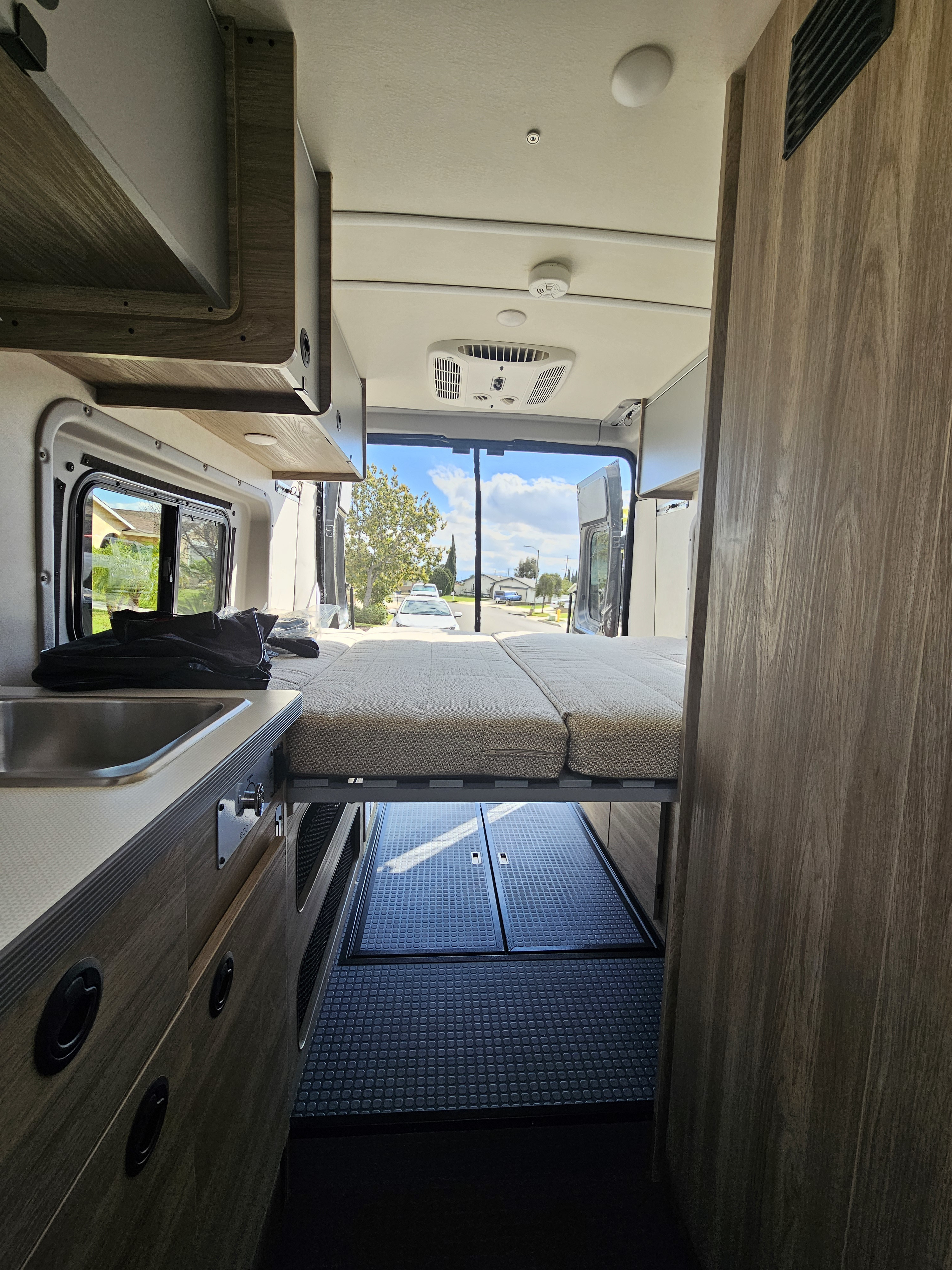 Modern RV rental interior: kitchen with sink, stove, microwave; living area with TV & storage. Compact & functional.. Winnebago Solis 2023