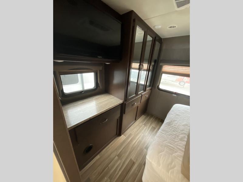 Inside an RV rental bedroom: features a comfy bed, wall-mounted TV, and dark wood storage cabinets/wardrobe.. Thor Motor Coach A.C.E 2018