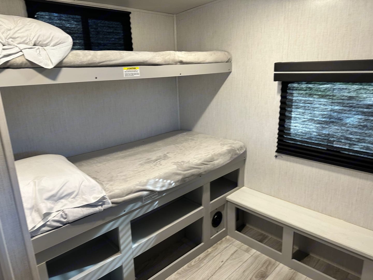 Bright RV rental interior showcasing practical bunk beds with under-bed storage and window blinds.. Heartland RVs North Trail 2022