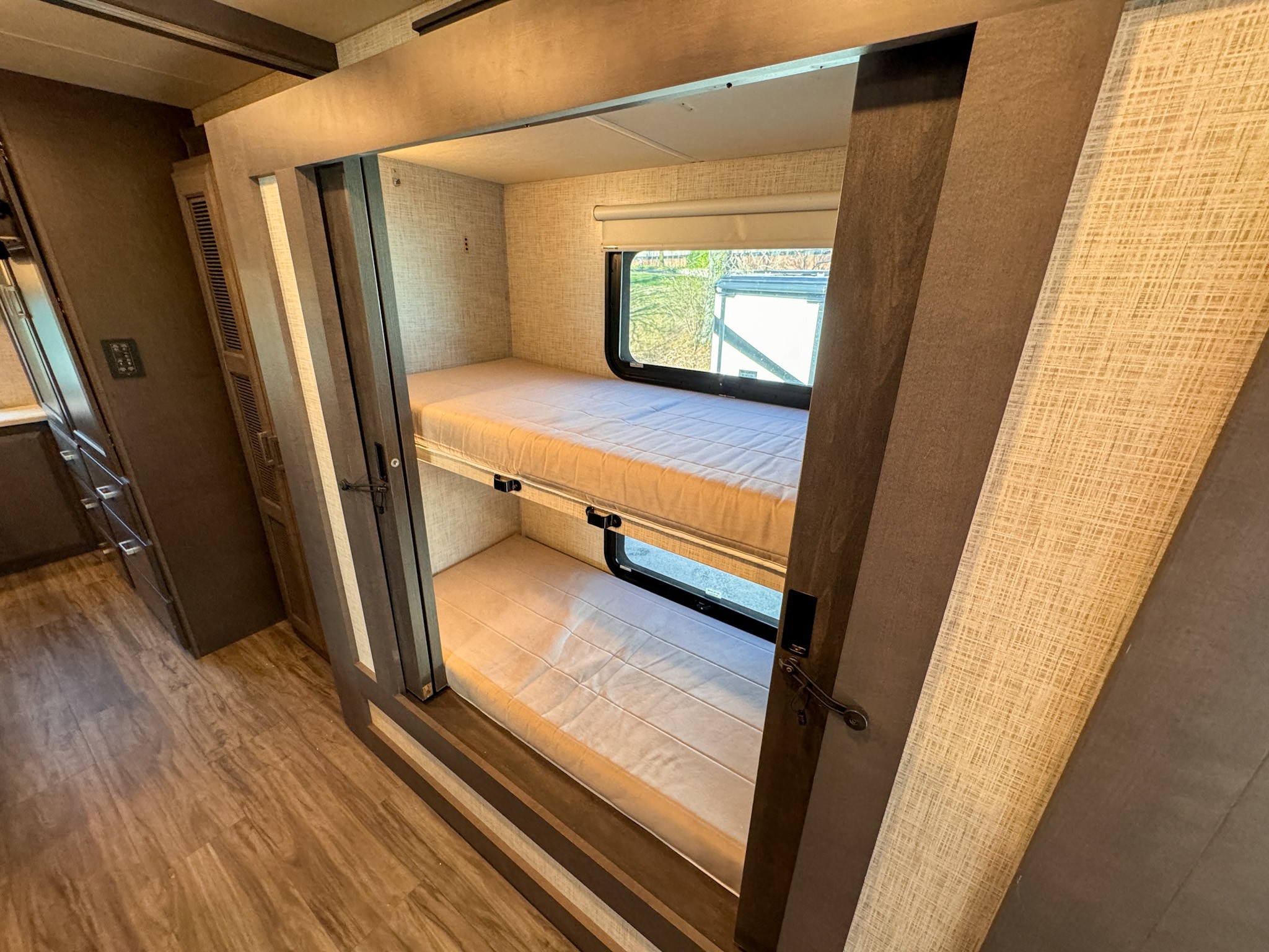 Inside this **RV rental**, find two bunk beds with mattresses, windows, and textured walls, offering a cozy sleeping area.. Thor Motor Coach Pasadena Super-C 2023