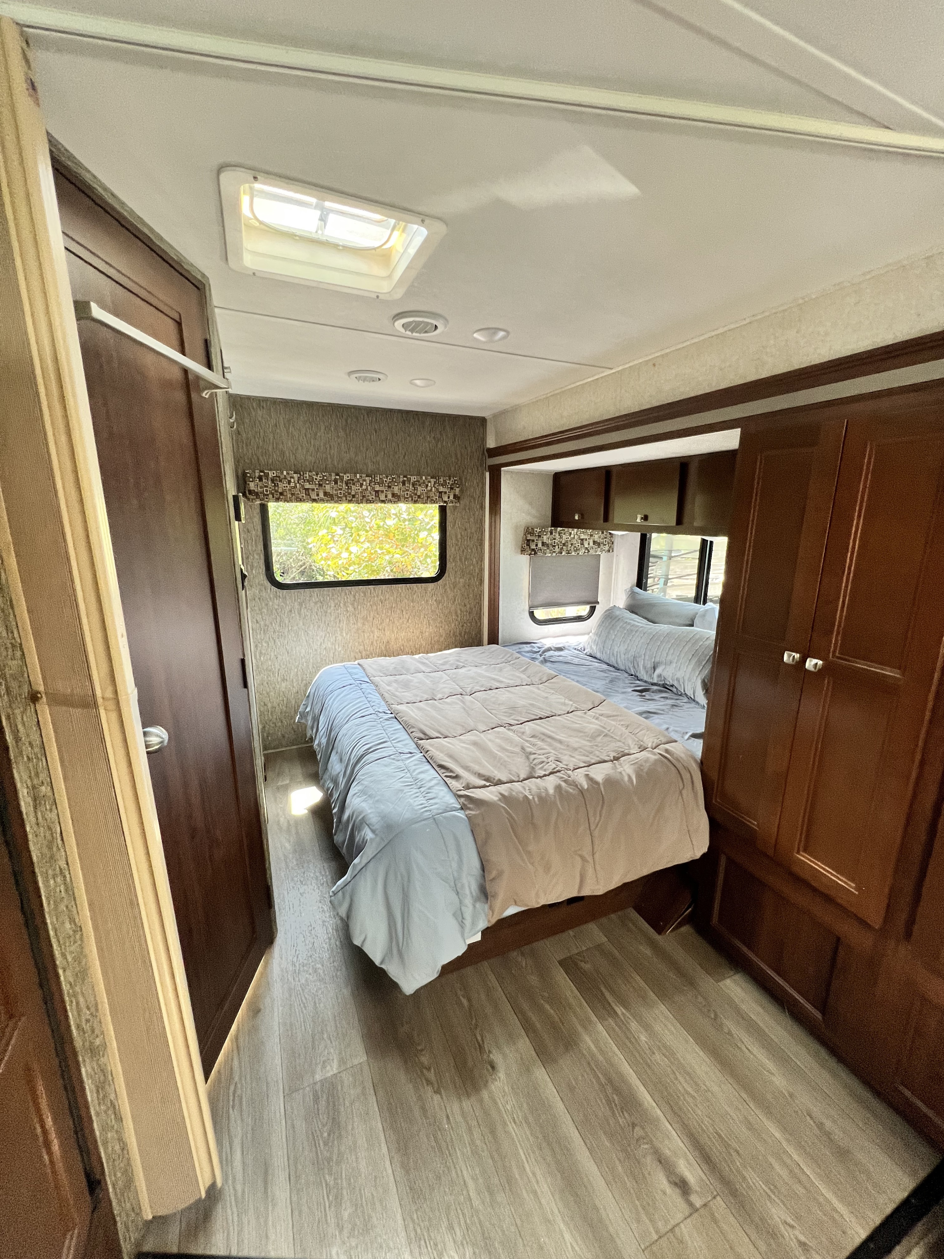Cozy RV rental bedroom with warm wood tones, a comfortable bed, and natural light from windows and a skylight.. Forester GTS 2018