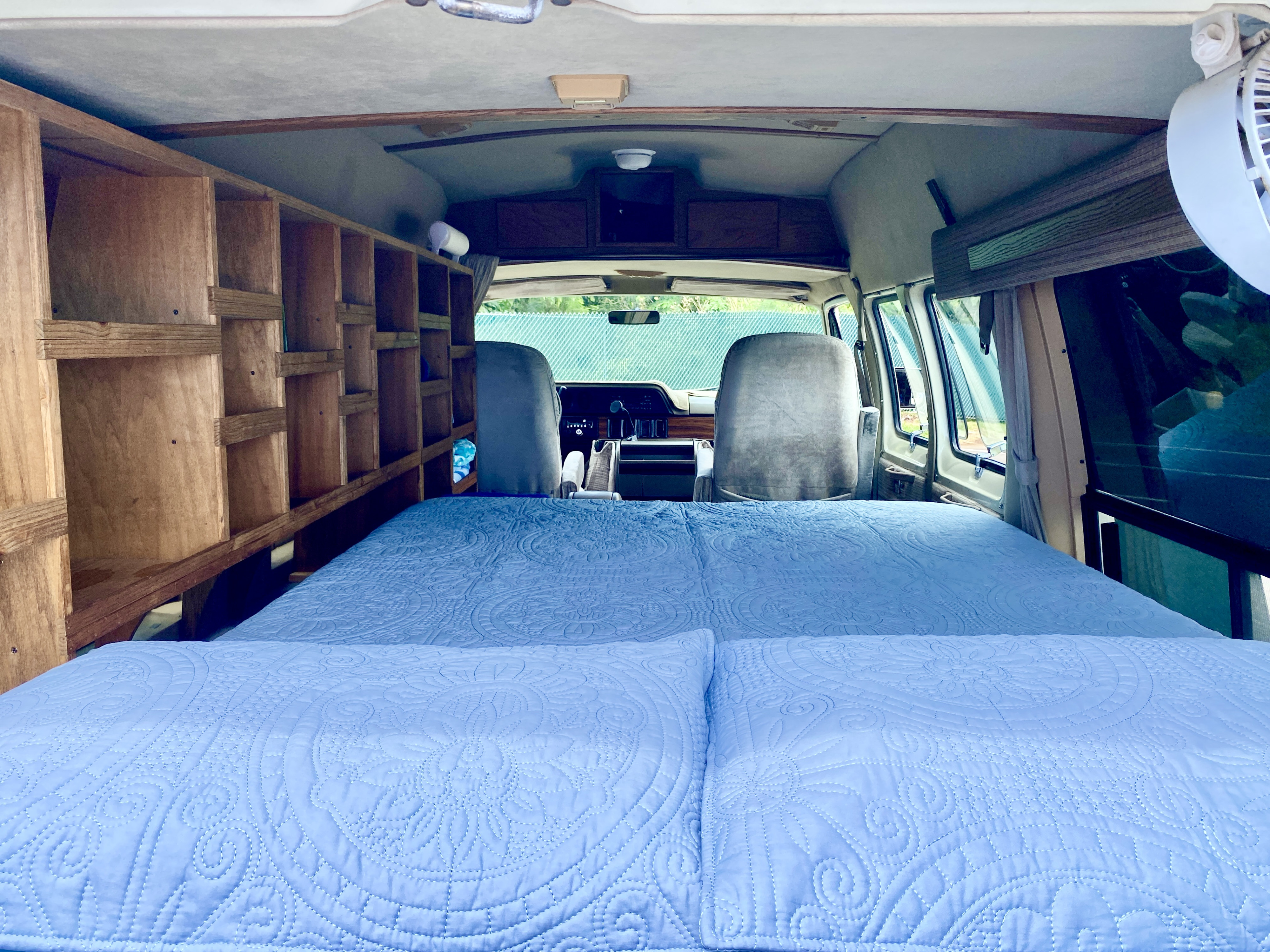 Explore this RV rental interior: a comfy bed, custom wooden shelving, and the front cabin view.. Dodge 230-515 1993