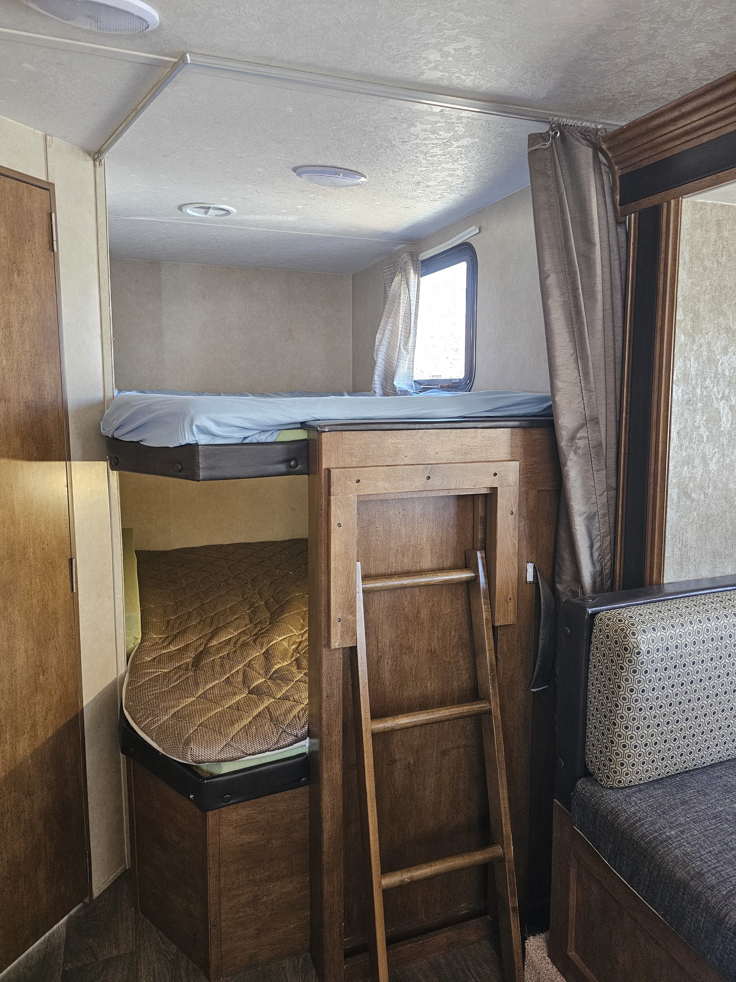 Cozy RV rental interior featuring bunk beds, a ladder, and a patterned dinette seating area, ideal for family trips.. Forest River Salem Cruise Lite 2017