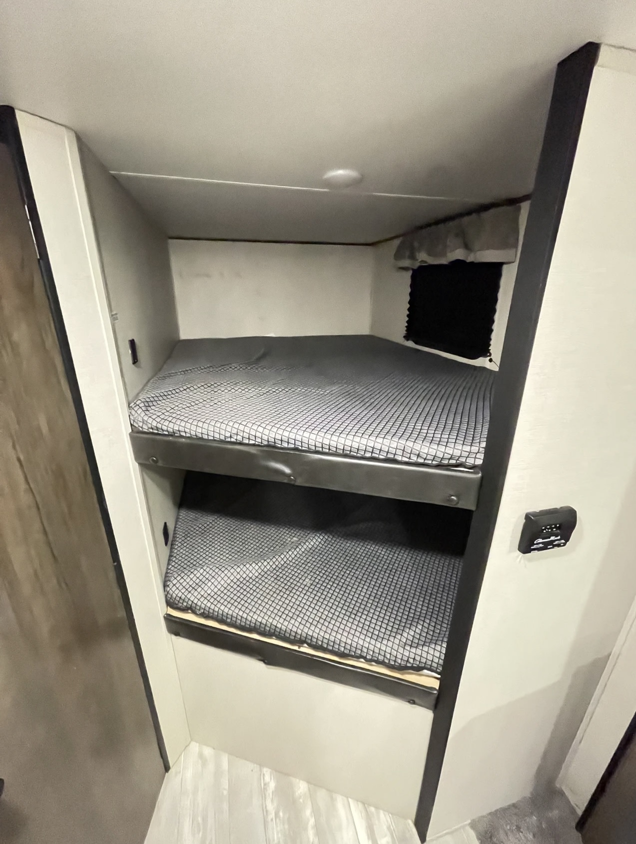 Compact RV rental interior featuring two comfortable bunk beds with patterned sheets and a window, ideal for travel.. Forest River PRIME TIME AVENGER 2021
