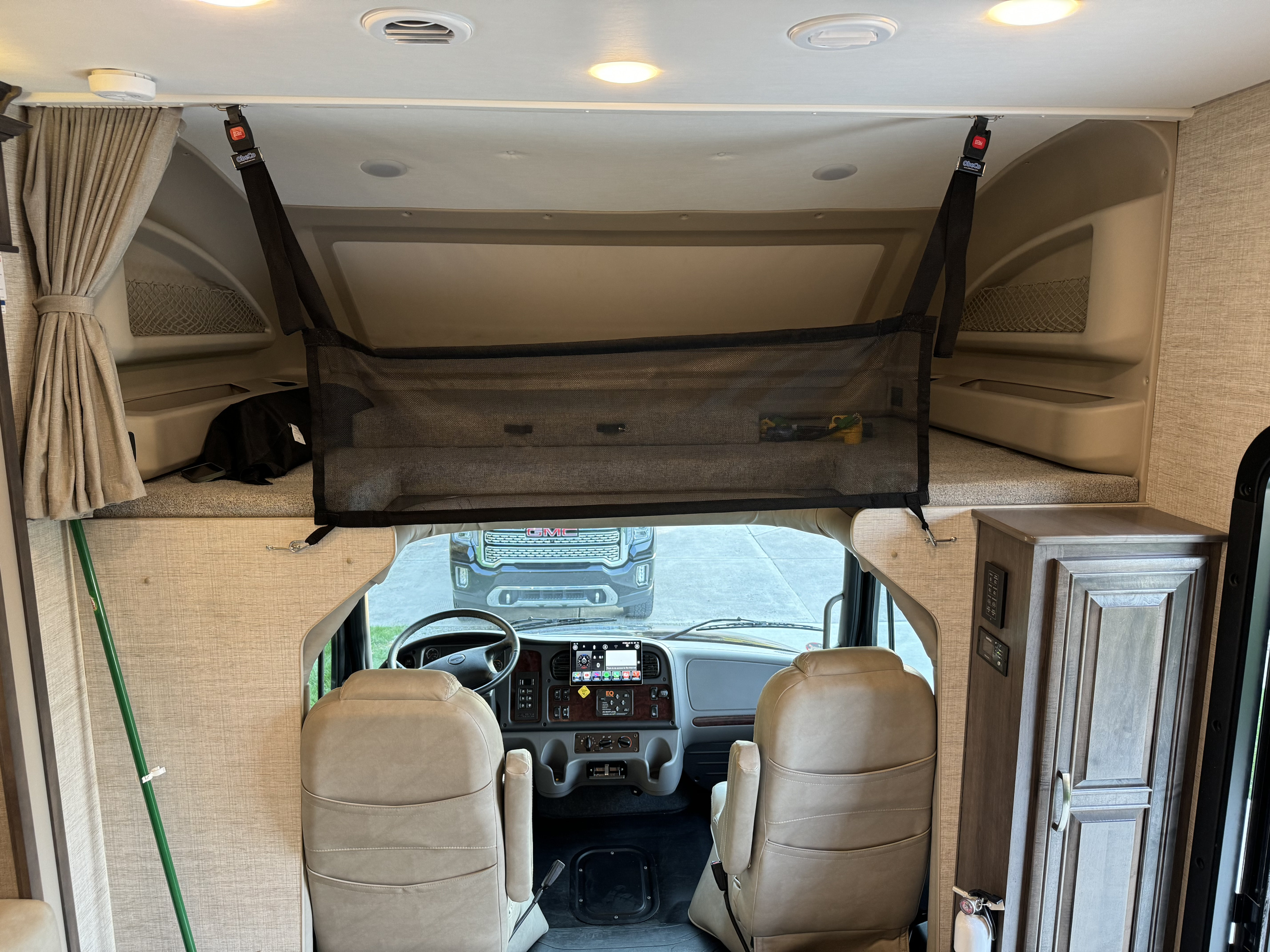 Interior of an **RV rental**: looking towards the cockpit and driver's area, with a large cab-over bunk and safety net.. Jayco Redhawk 2022