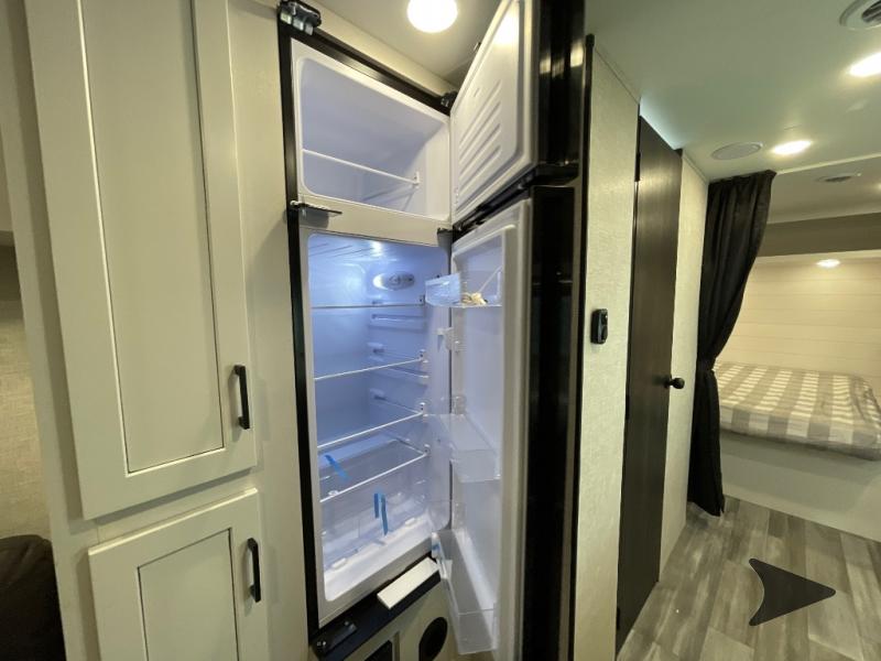 Explore this RV rental's interior: an open fridge, light cabinets, and a cozy bedroom beyond the privacy curtain.. Jayco Jay Flight 2024