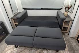 Explore comfort in your RV rental! A dark gray pull-out sofa bed is fully extended in this modern RV living space, ready for guests.. Forest River Palomino Puma 2023