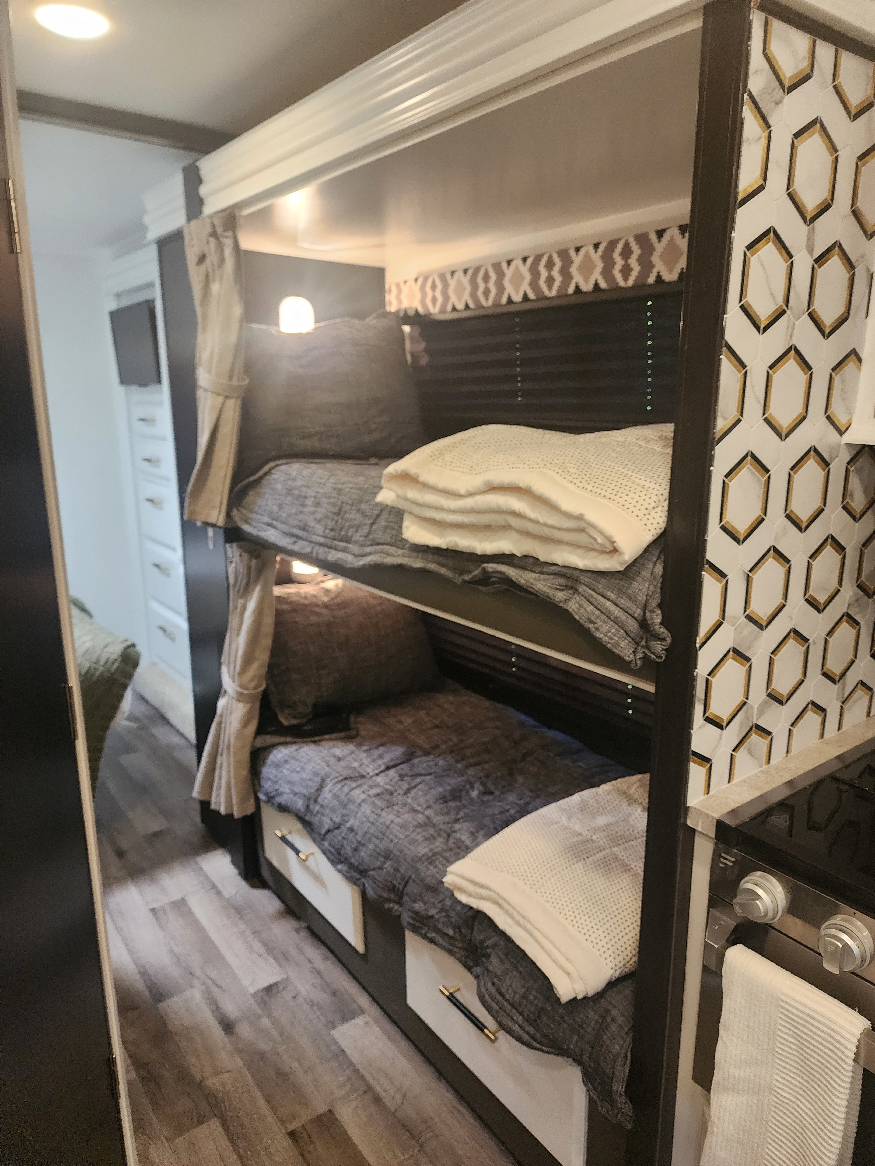 RV rental bunk beds feature soft bedding, reading lights, and under-bed storage. Modern tile accents the comfortable sleeping area.. Entegra Coach Odyssey 2021