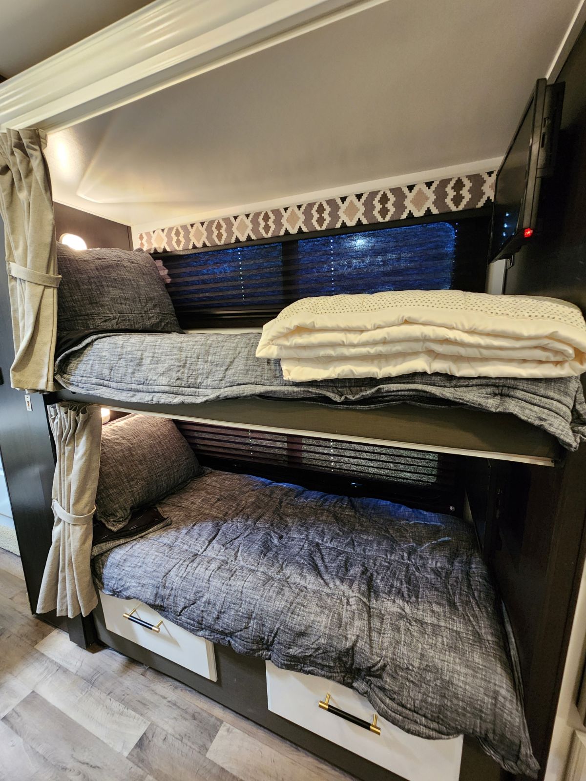 This RV rental offers cozy bunk beds with curtains, TV, and storage drawers, ideal for a comfortable stay.. Entegra Coach Odyssey 2021