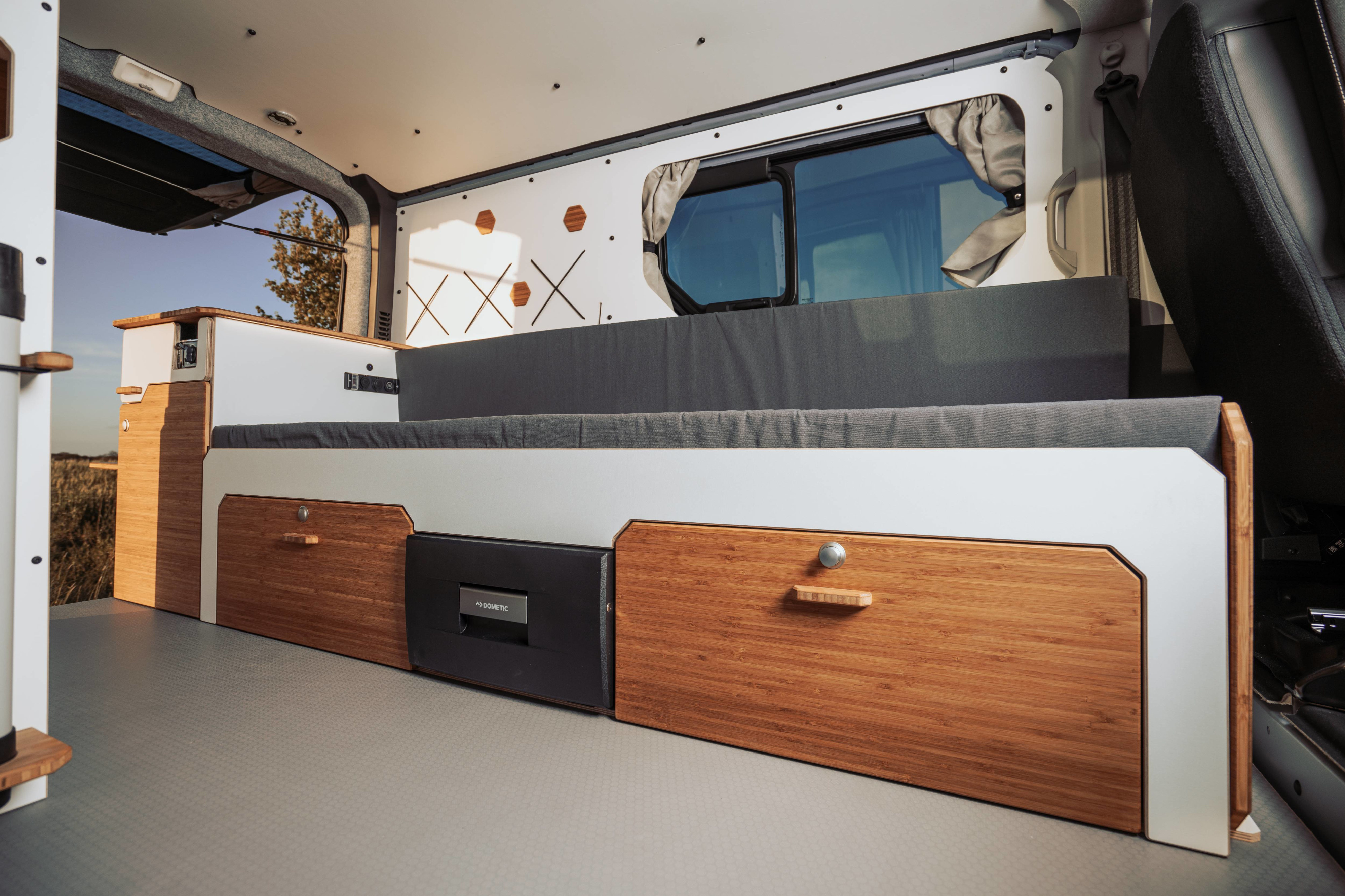 Modern RV rental interior with bed, bamboo storage, and a Dometic fridge for comfortable adventures.. Renault Trafic 2025