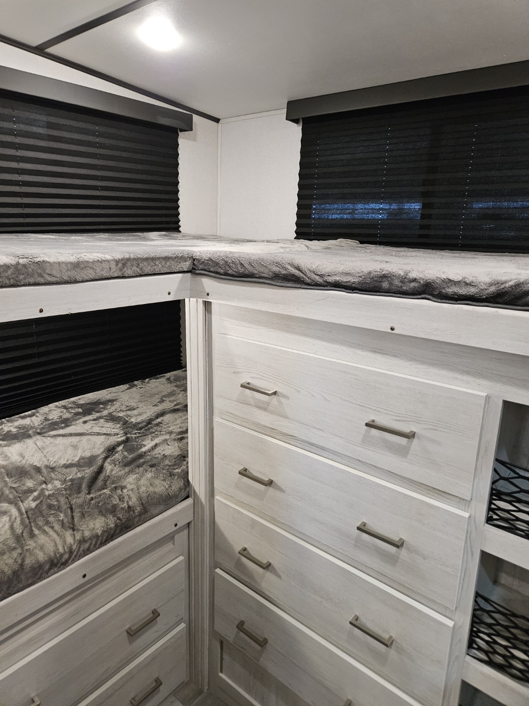 Inside an RV rental: L-shaped bunk beds with integrated storage drawers and privacy blinds.. Keystone RV Sprinter 2023