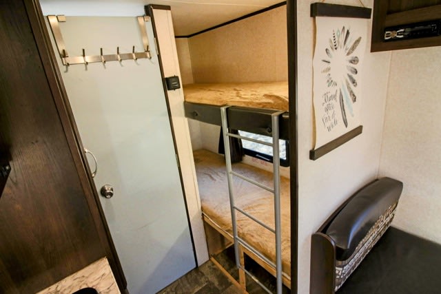 RV rental interior: cozy bunk beds with ladder, small seating area, and handy door hooks.. Jayco Jay Flight SLX 2017