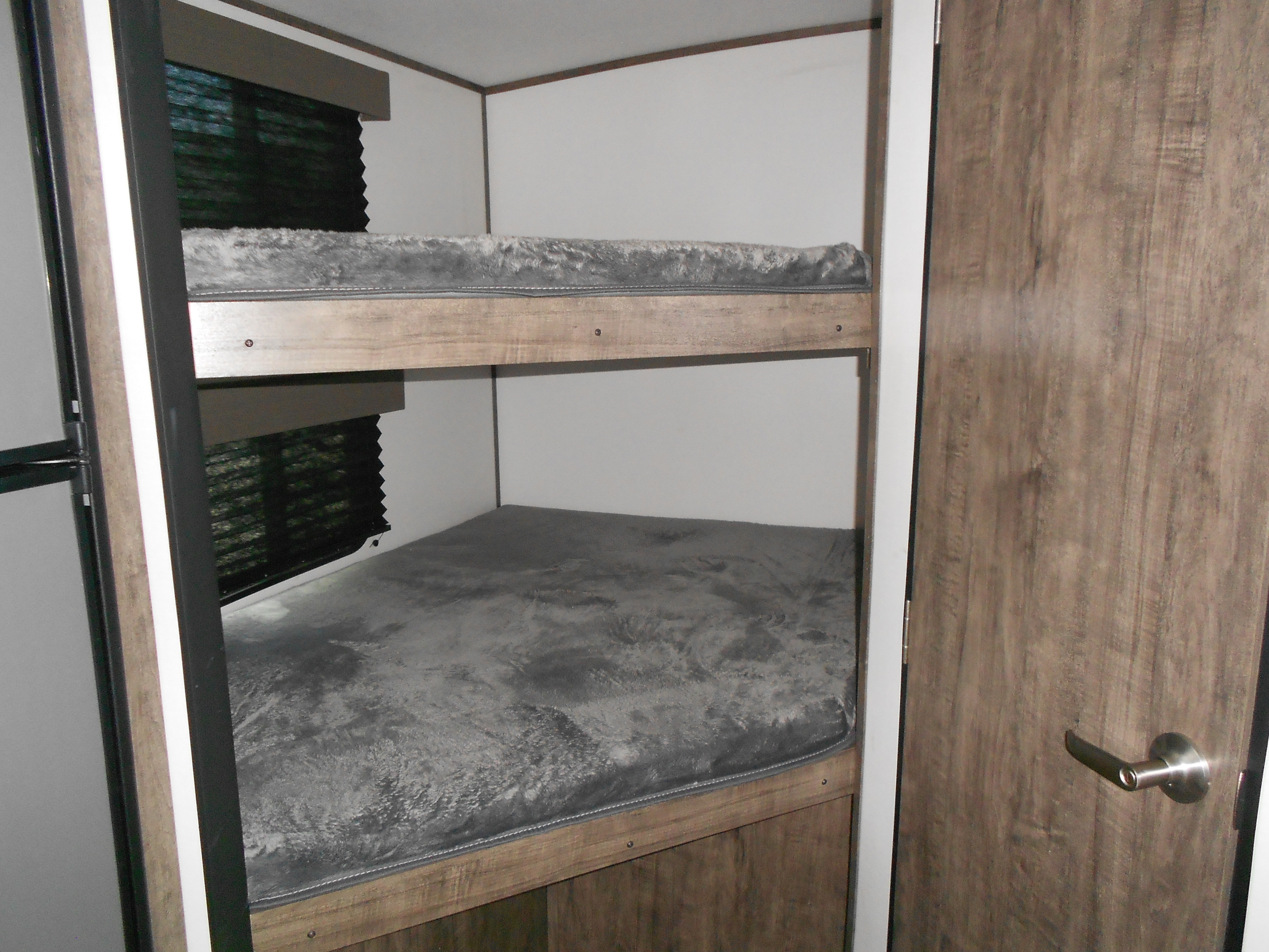 Inside an RV rental: Two bunk beds with grey plush mattresses, a window, and a door, perfect for family sleeping.. Xplorer Xplorer 240BHX 2023