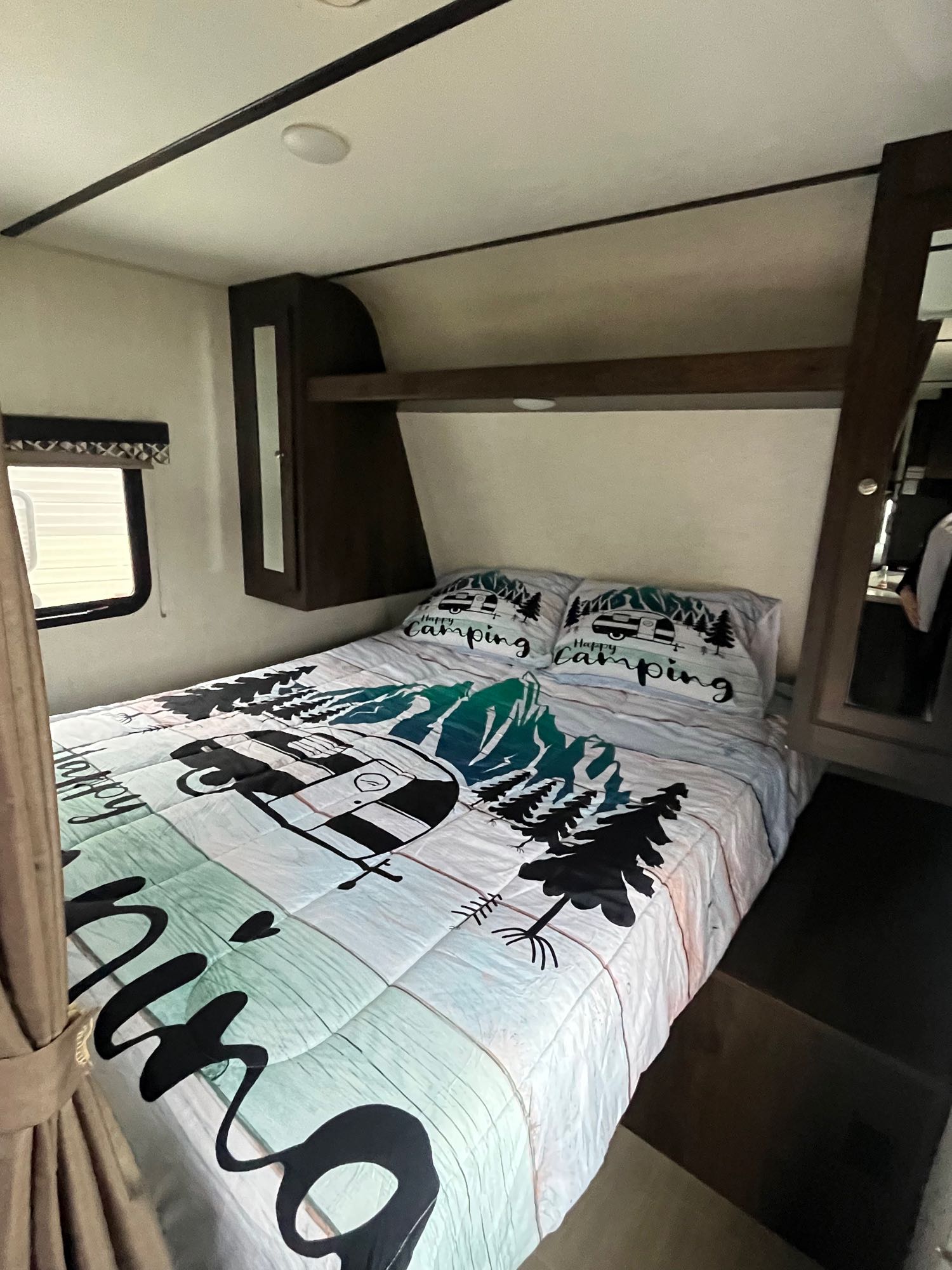 Cozy RV rental bedroom with "Happy Camping" themed bedding, overhead cabinets, and a window for comfortable travel.. Starcraft Launch Outfitter 2019