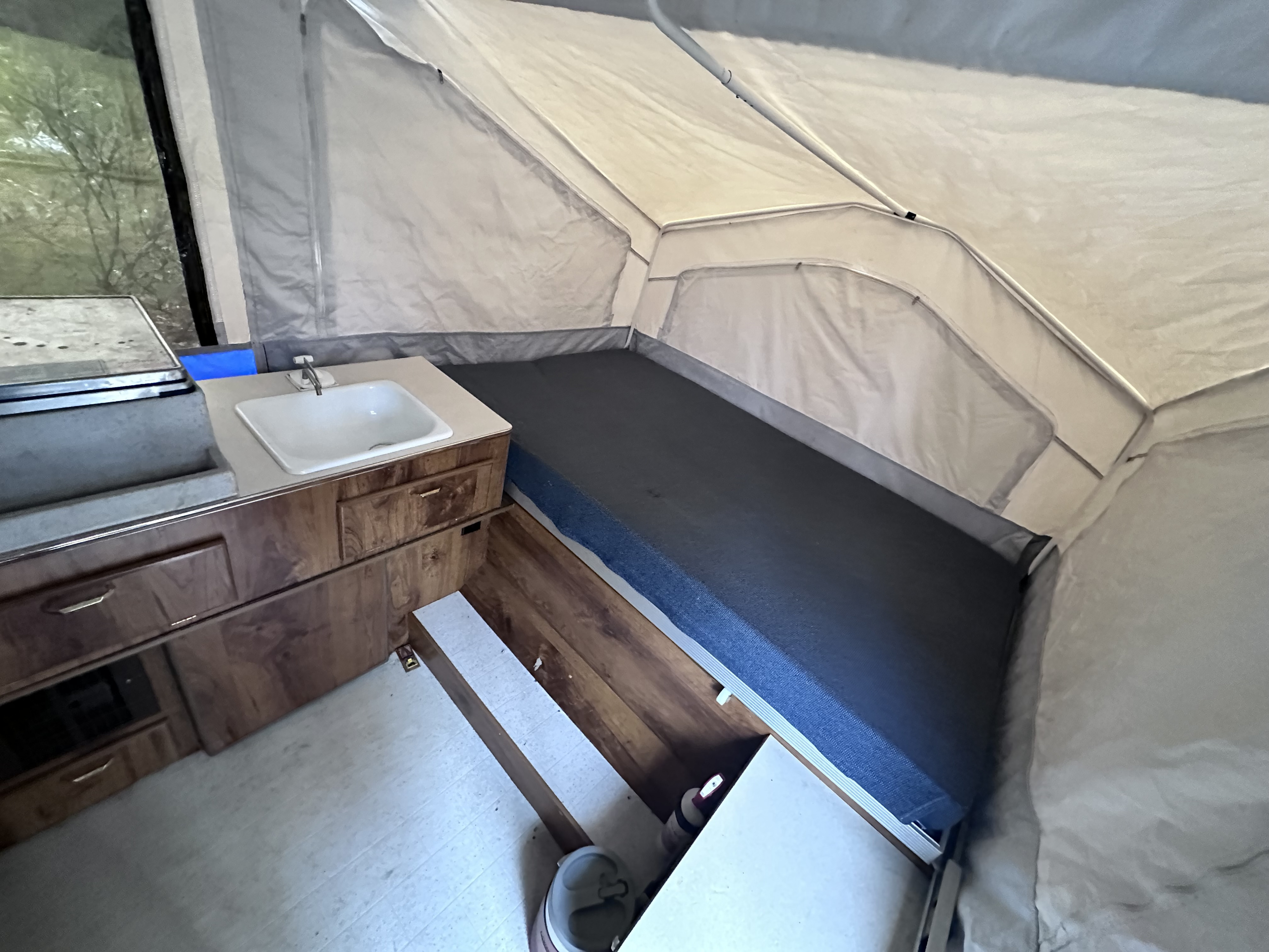 Inside an RV rental: Compact pop-up camper interior with kitchen, sink, and comfy bed for your next adventure.. Forest River Rockwood Freedom 2012