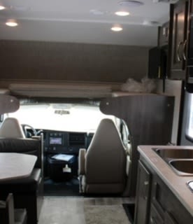 Explore this clean RV rental interior! Features a kitchen, dinette, and over-cab bunk, ideal for your next road trip.. Jayco Redhawk 2023