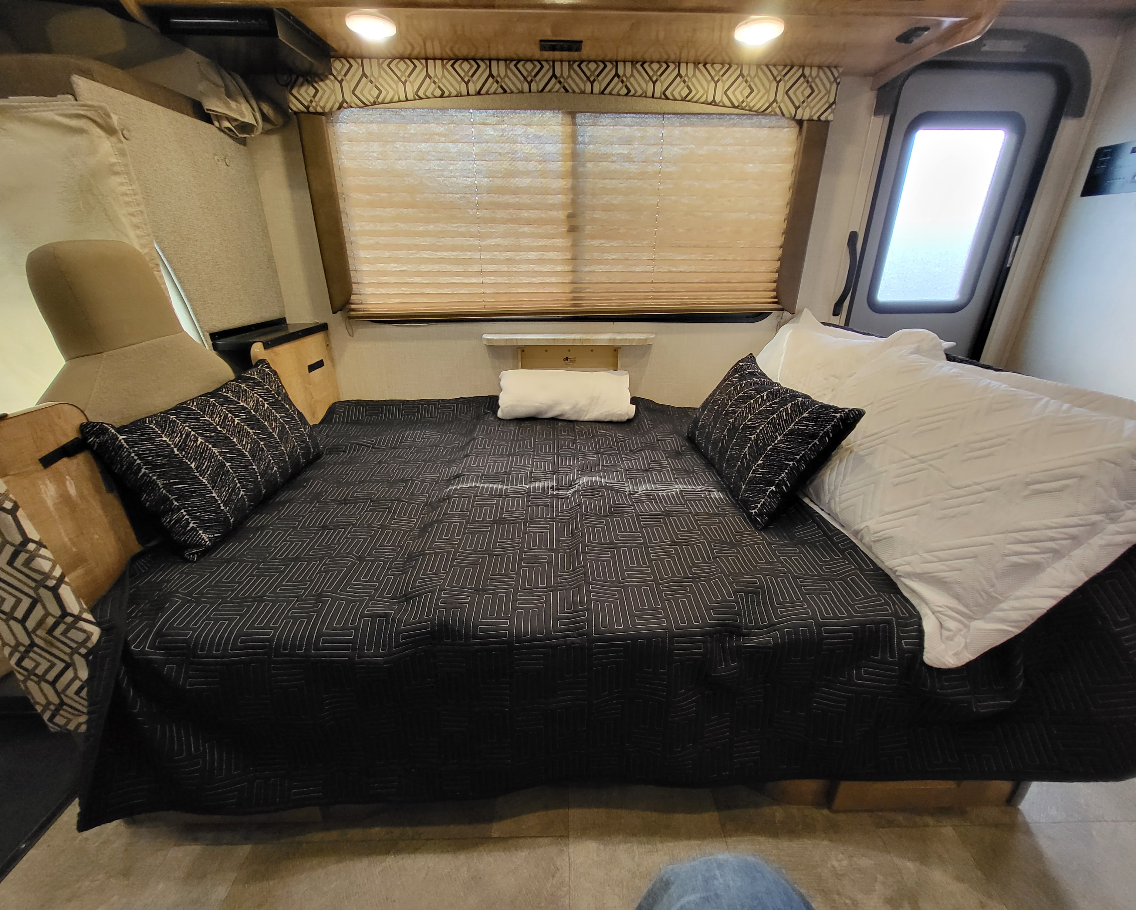RV rental interior showcasing a comfortable bed with dark patterned bedding, white pillows, and window blinds.. Coachmen RV 260RS Ford 4500 2020