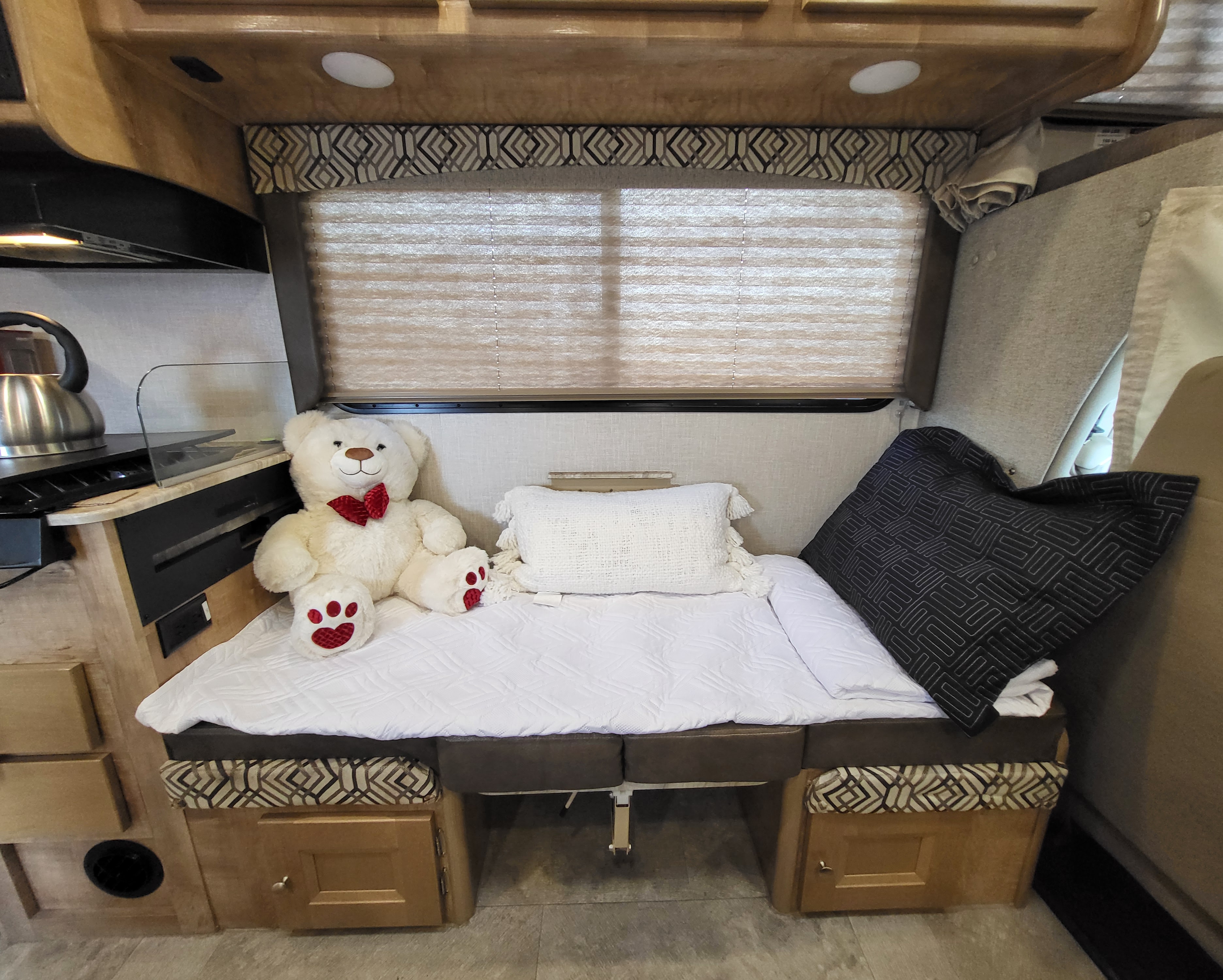 Cozy RV rental interior with a decorated sleeping area featuring a white teddy bear, pillows, and a nearby kitchen.. Coachmen RV 260RS Ford 4500 2020