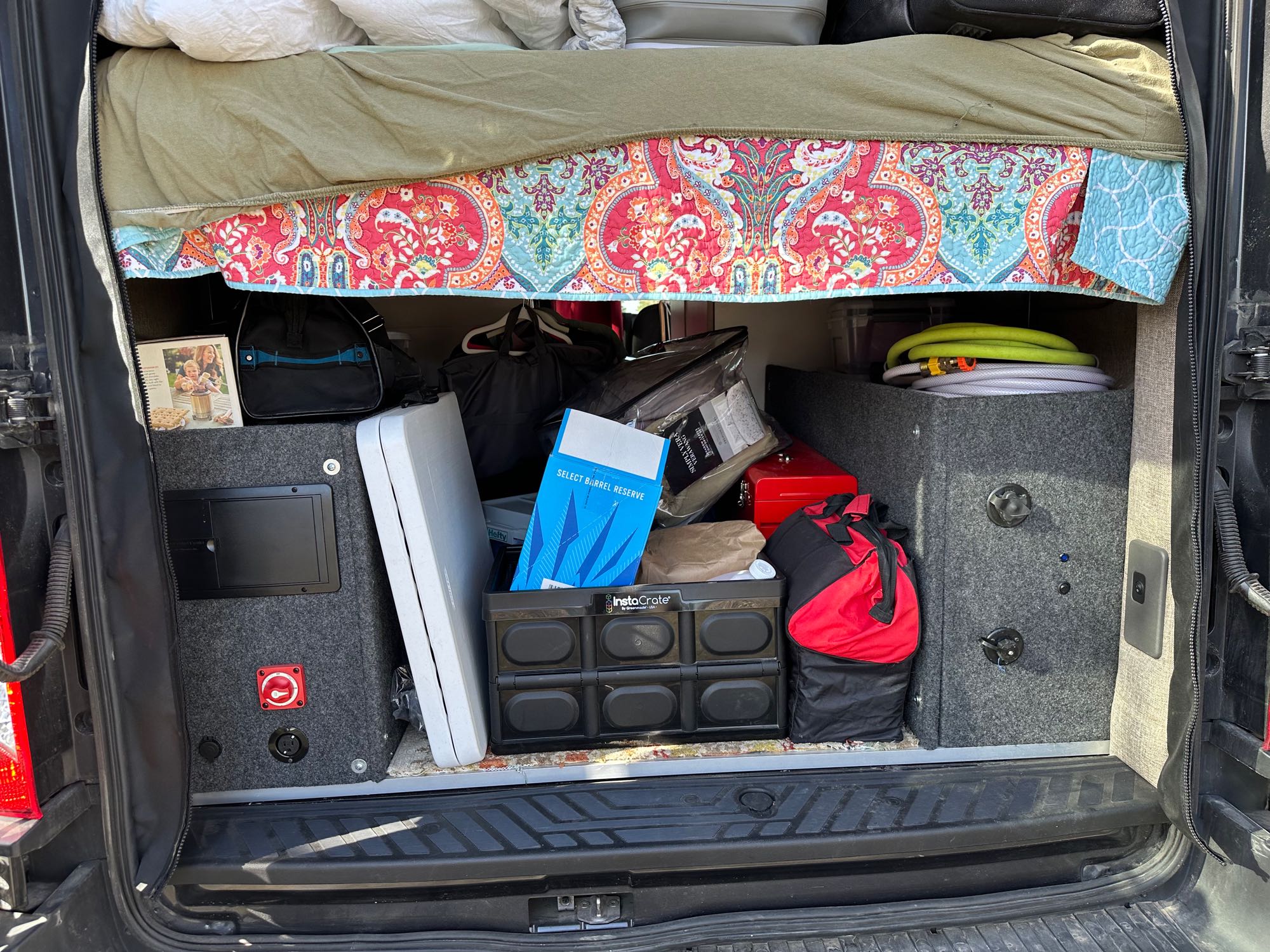 Organized **RV rental** interior with under-bed storage showing electrical, hoses, bags, and folding crates.. Ford Transit 2020