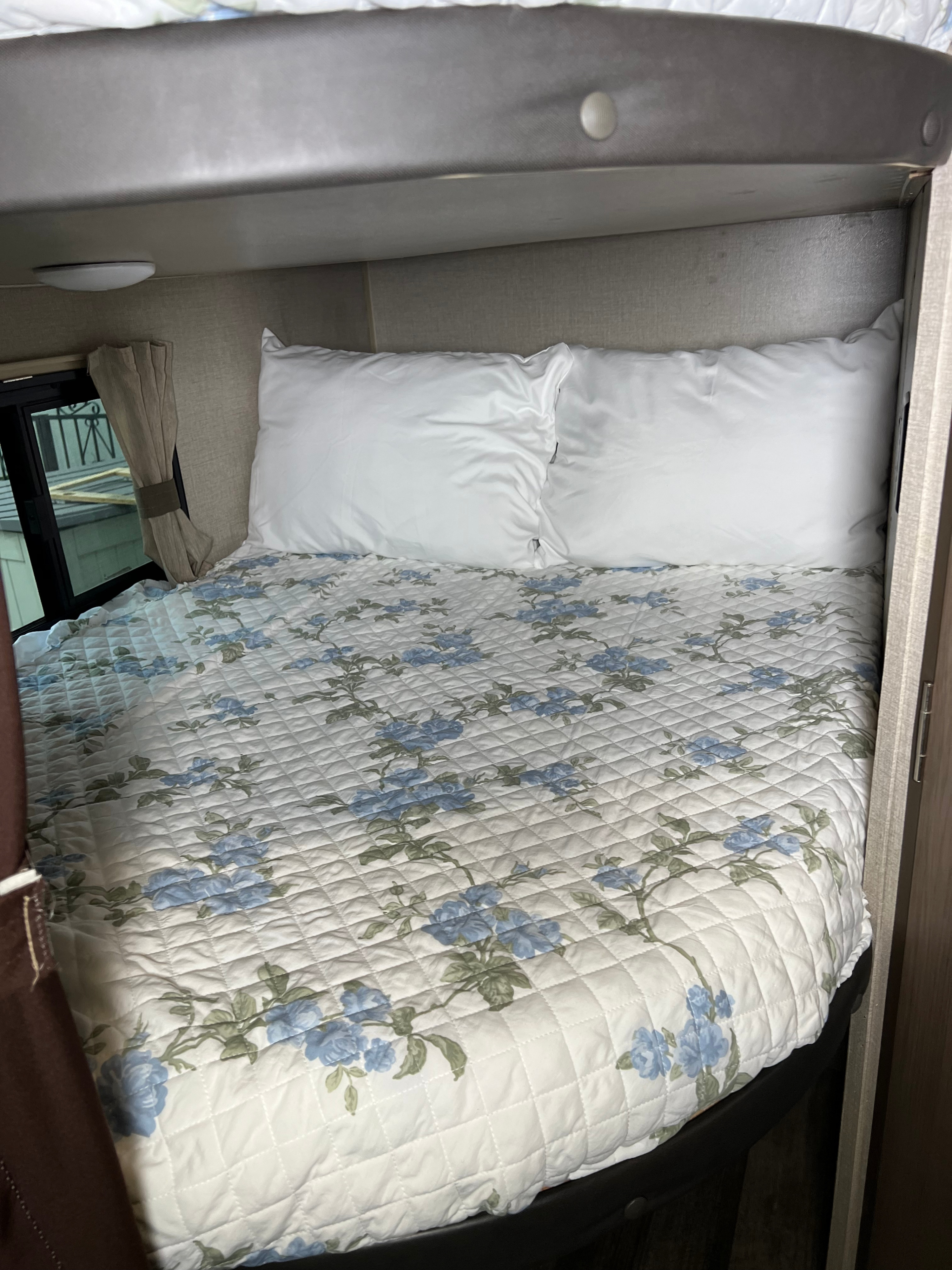 Comfortable RV rental bed featuring a white quilted floral comforter and white pillows, tucked beneath an upper bunk.. Coachmen Catalina Summit 2021