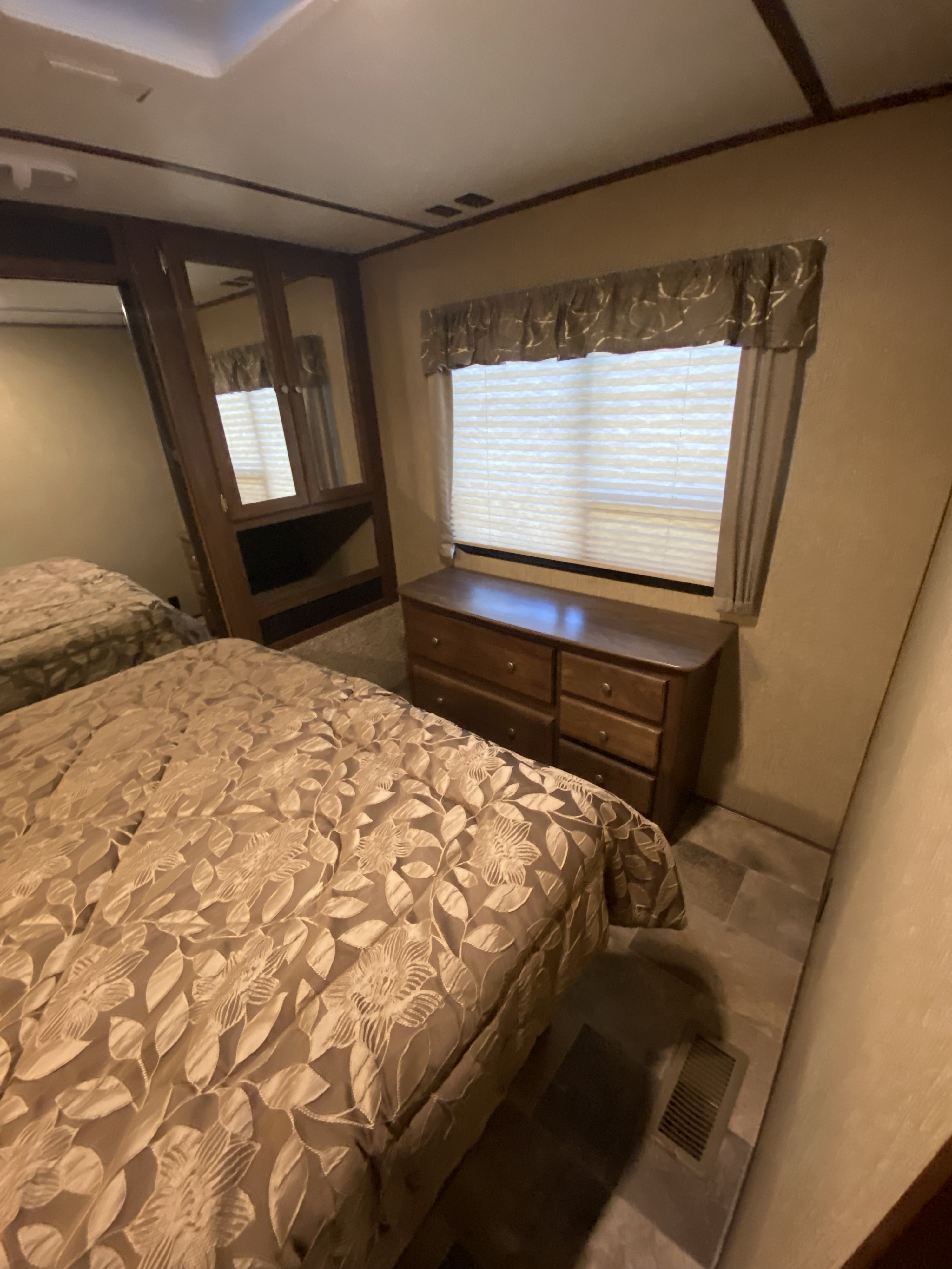 Cozy RV rental bedroom: two beds, dresser, and window with blinds. Functional interior for your travels.. Keystone RV Sprinter Campfire Edition 2018