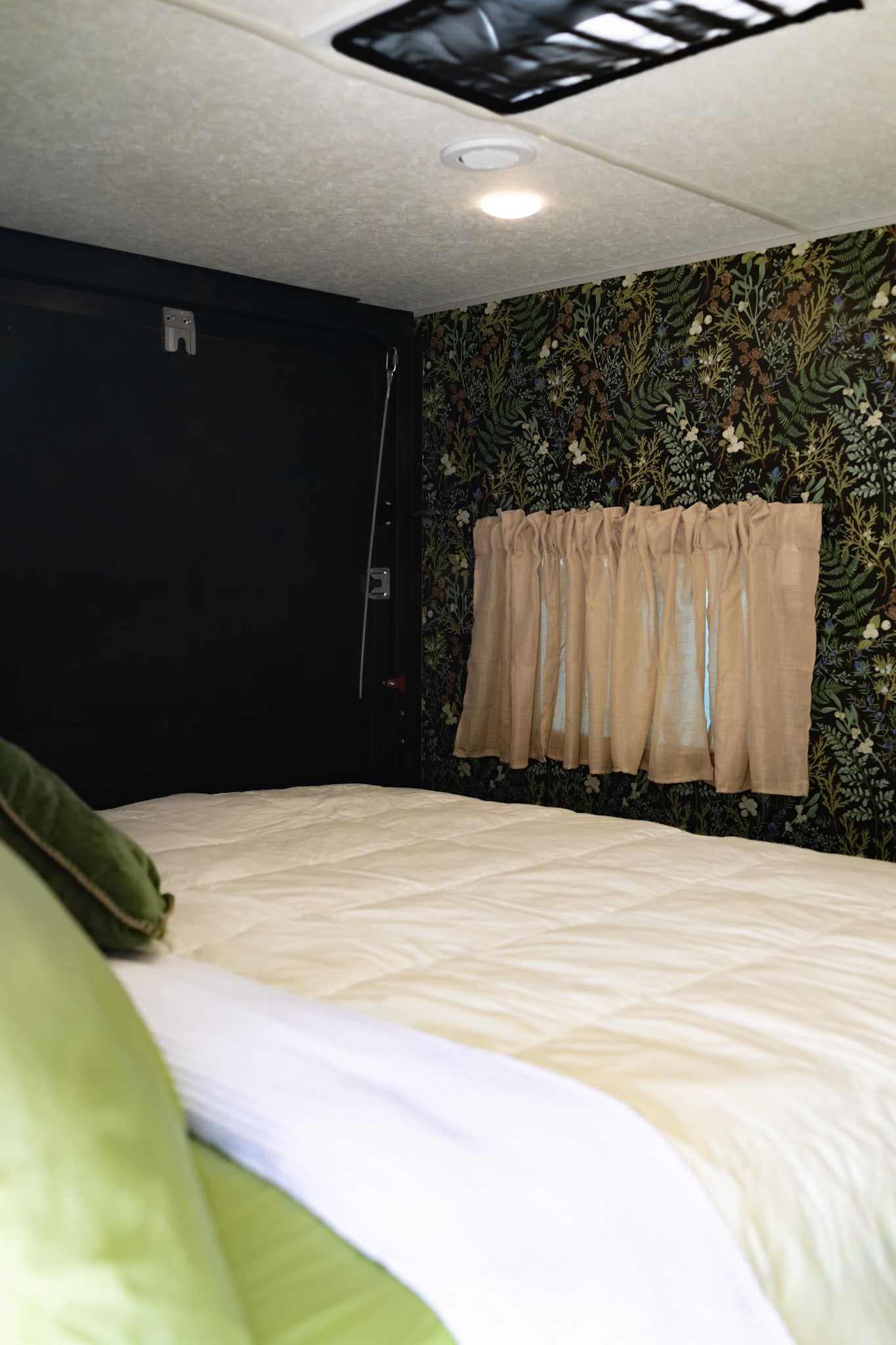 A cozy RV rental bedroom interior with a comfortable bed, botanical wallpaper, and light curtains, offering a unique and inviting space.. Forest River Ozark 2022