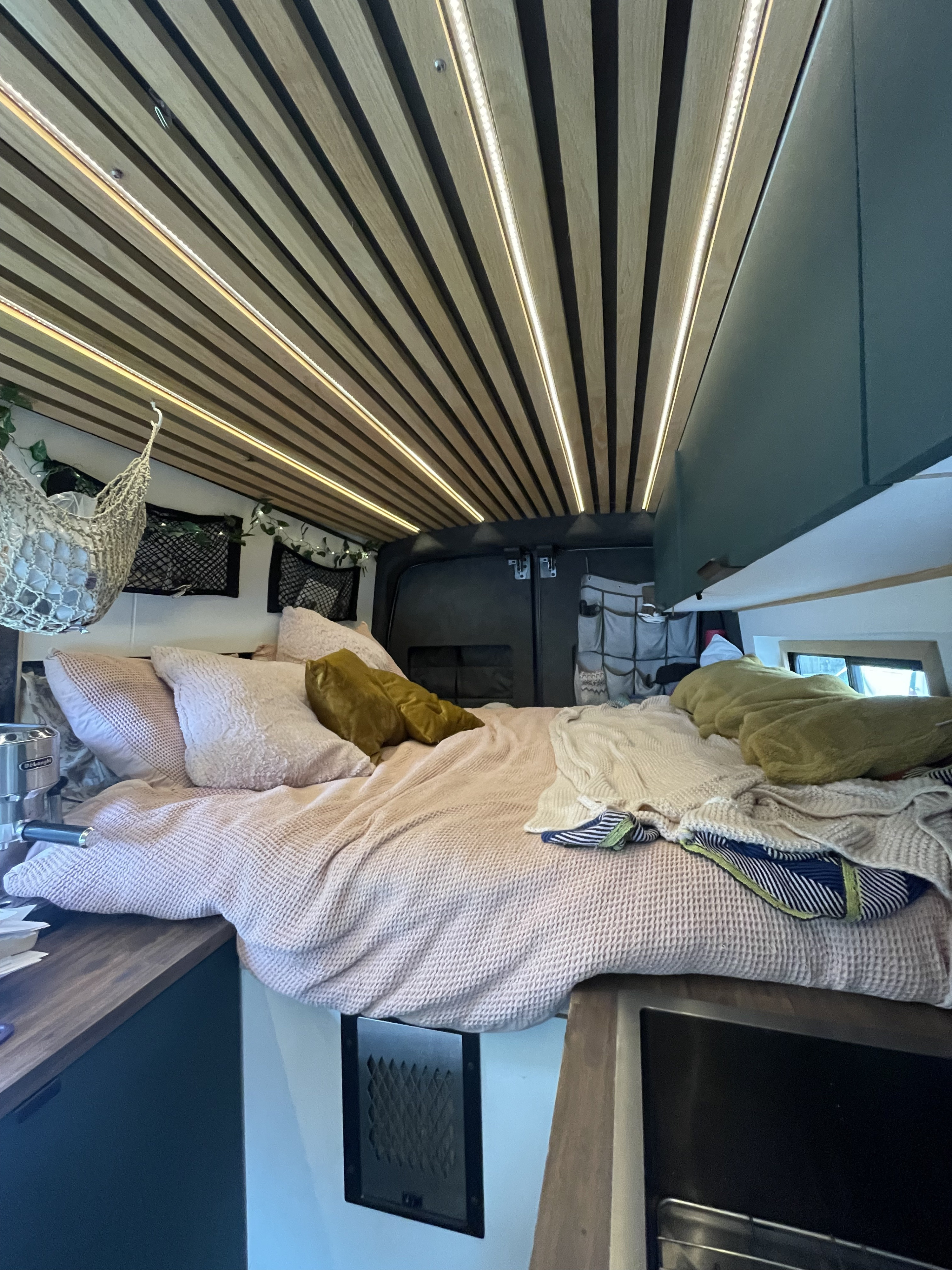 Step inside this cozy rv rental featuring a comfortable bed, stylish wood-slat ceiling with LED lighting, and smart storage.. Ford Transit 2022