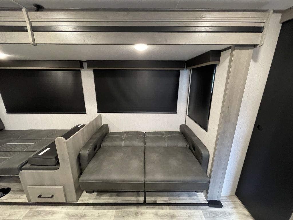 RV rental interior with flexible seating: a gray dinette converts to a bed, plus a fold-flat sofa, under blackout shades.. Keystone Kodiak 2022