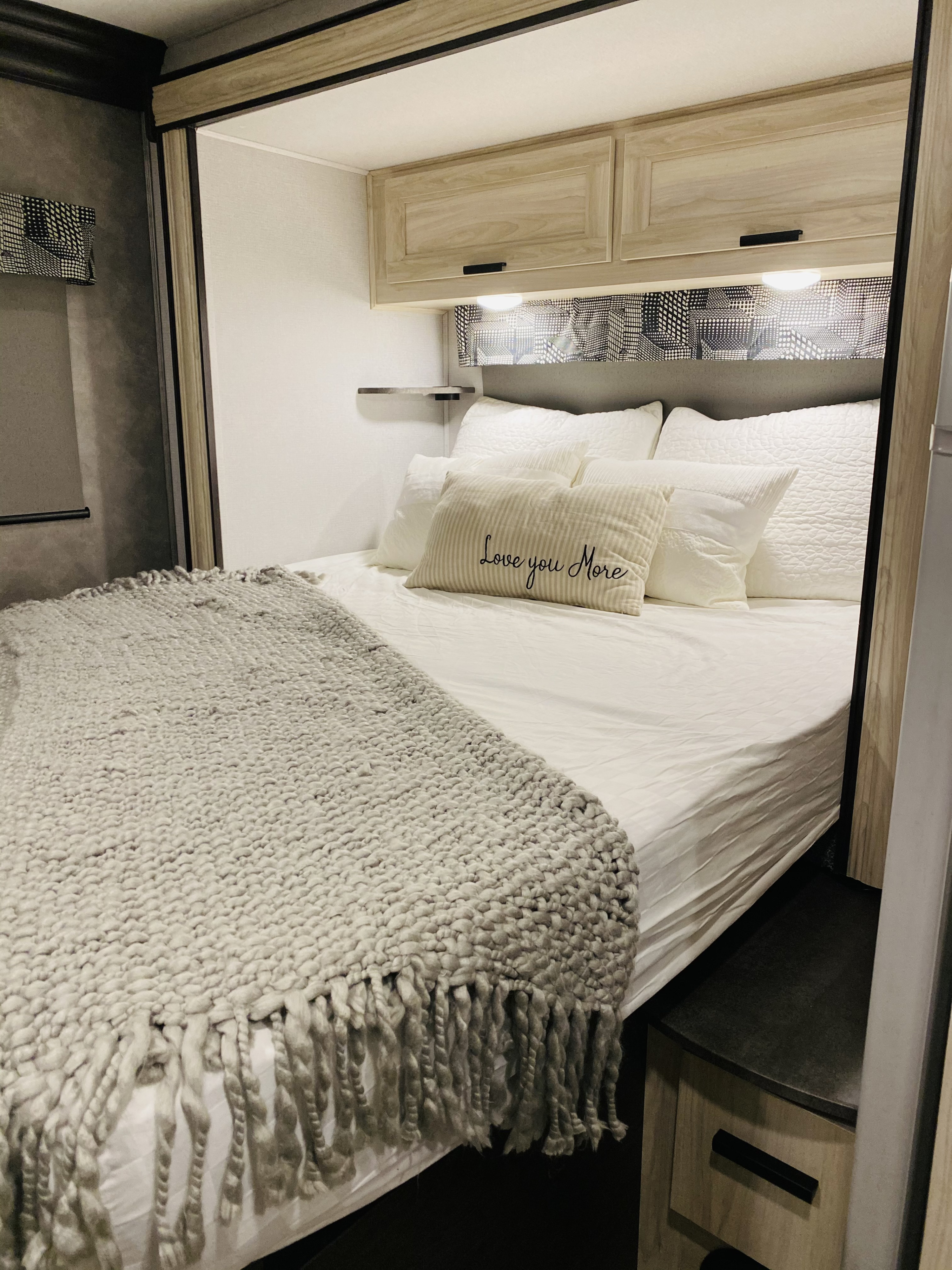 Your comfy RV rental bedroom: cozy bed with white linens, "Love you More" pillow, and grey knit throw.. Forester LE 2021