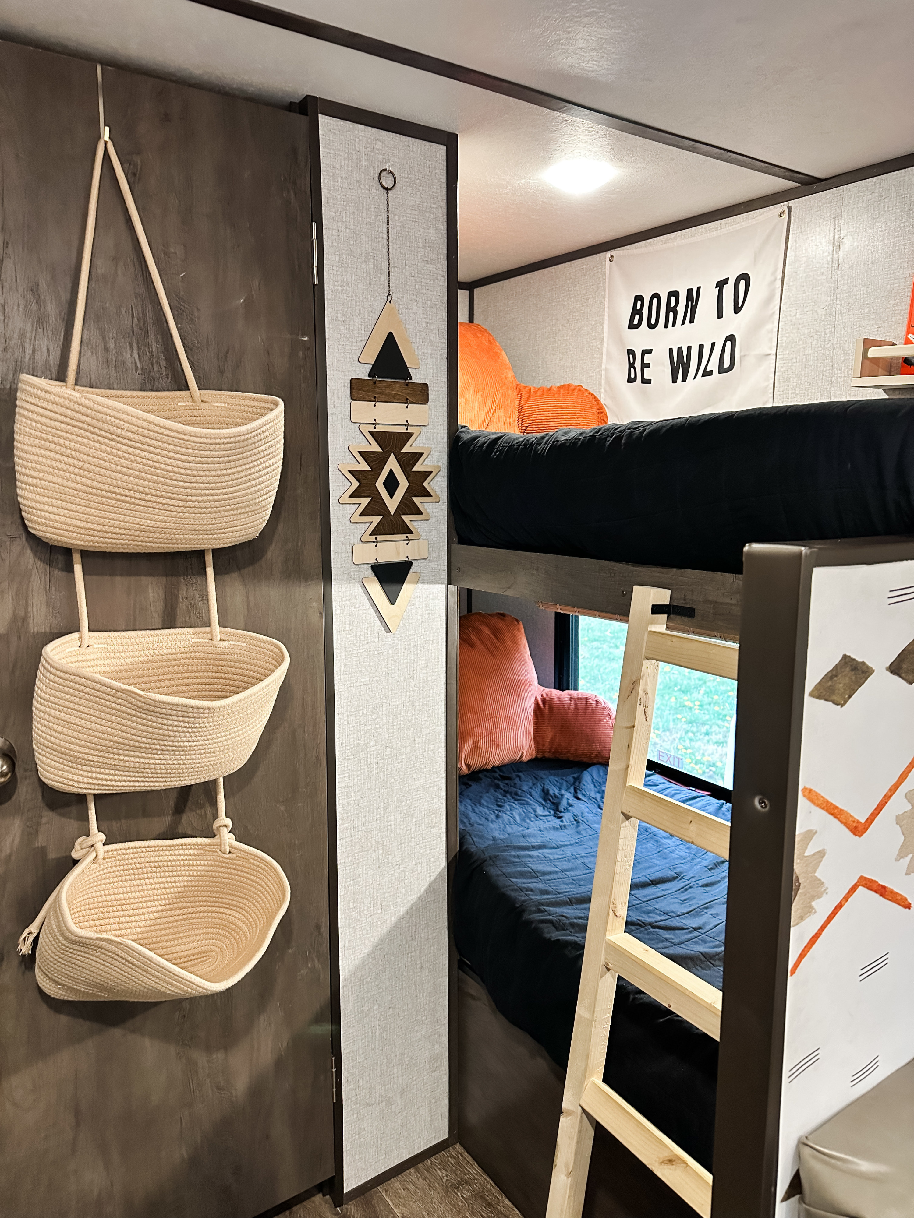 This RV rental features a cozy bunk bed setup with rope storage, a "Born to be Wild" banner, and tribal-inspired decor.. Dutchmen Coleman Lantern LT 2021