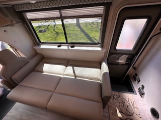 RV rental: Spacious RV interior showcasing a convertible sofa bed, large window, and controls for a comfortable journey.. Thor Coleman 2024