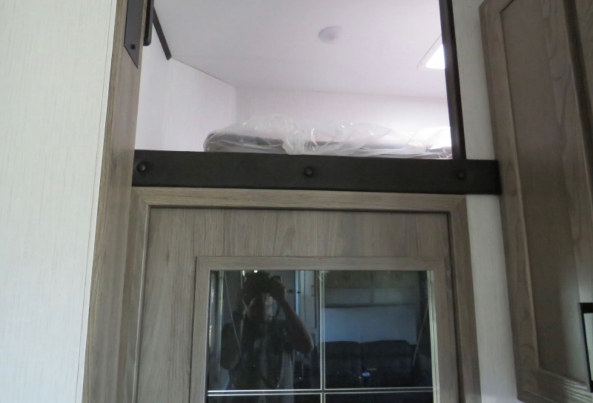 RV rental: Interior shows an overhead sleeping loft with items in plastic, above a wood-grained door with reflective glass.. Heartland RVs Gravity Toy Hauler 2022