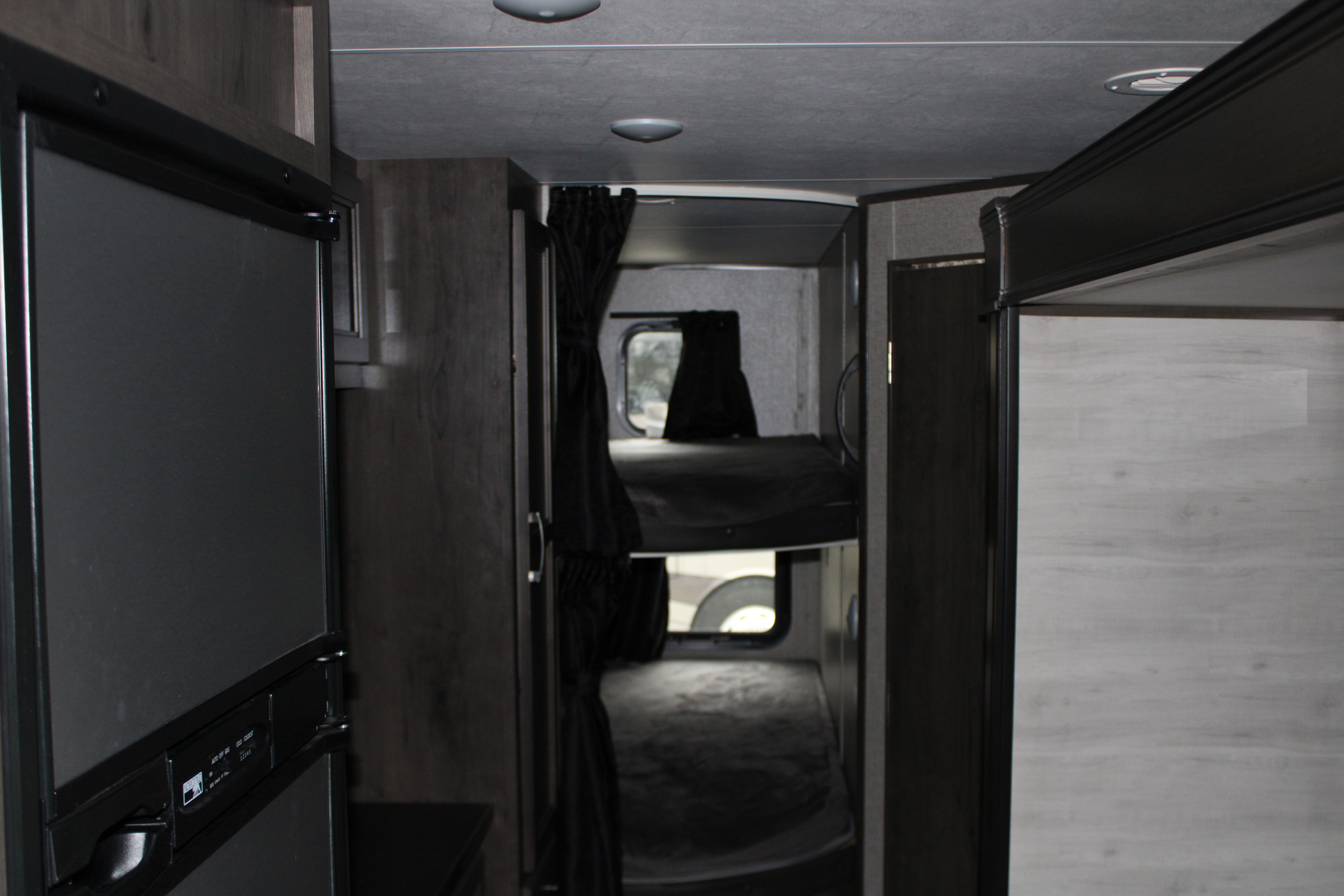 RV rental interior view: A modern RV bunkhouse hallway with a dark gray refrigerator unit on the left.. Jayco Jayflight SLX 8 2021