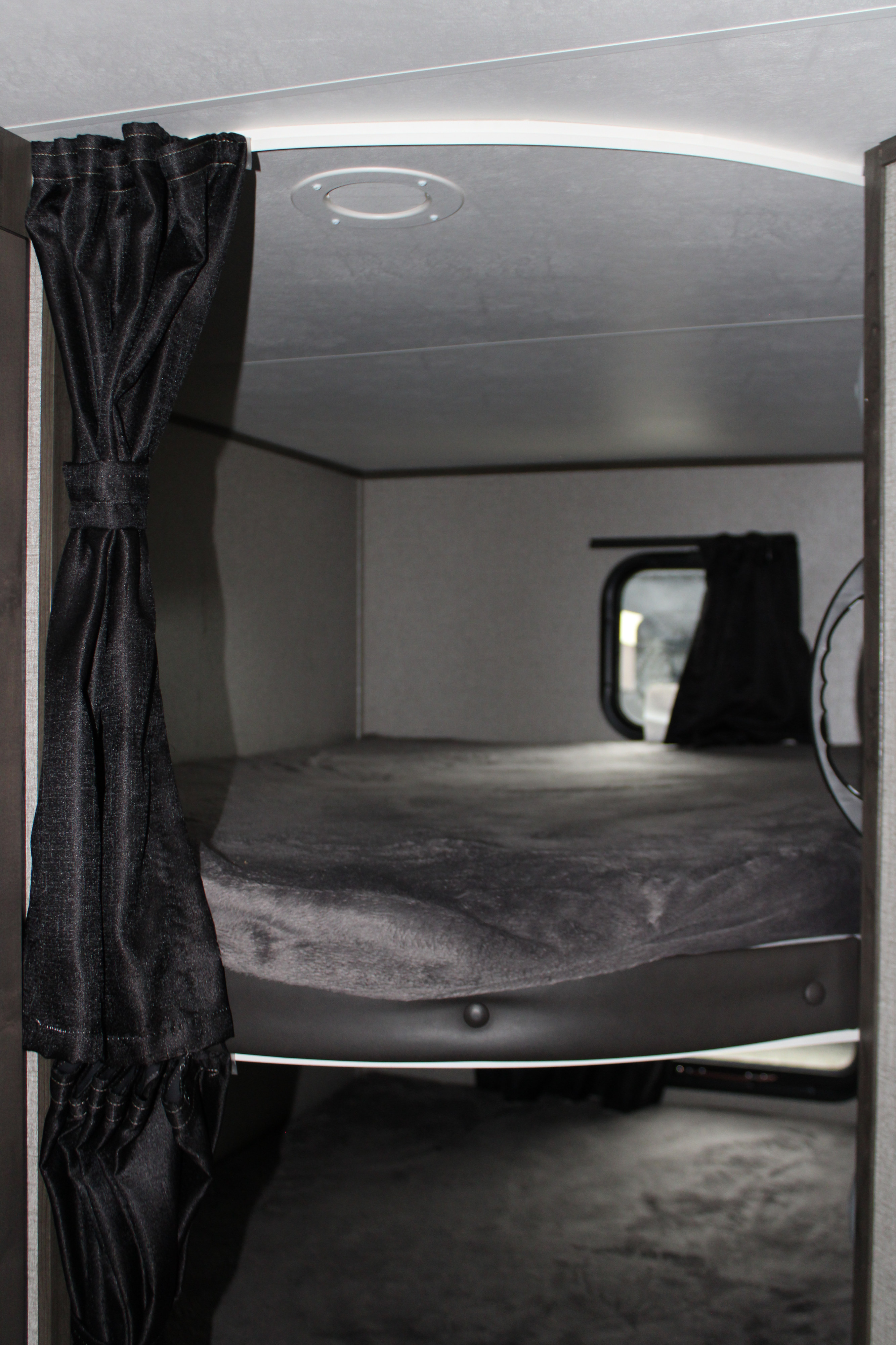 Inside an RV rental: a compact and cozy bunk bed with a dark comforter and window, offering a private sleeping space.. Jayco Jayflight SLX 8 2021