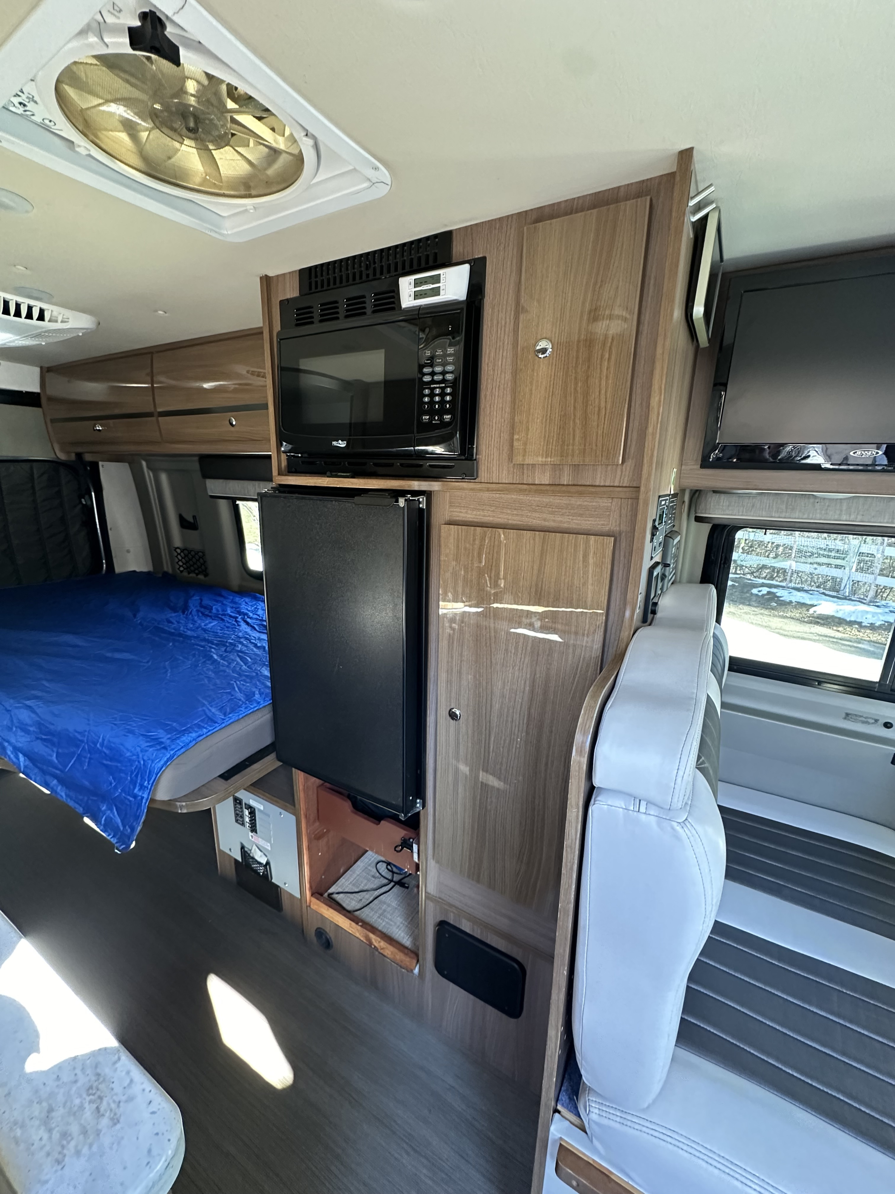 Spacious RV rental interior: bed, kitchenette with microwave & fridge, storage, and seating area. Ready for adventure!. Winnebago Travato 2016