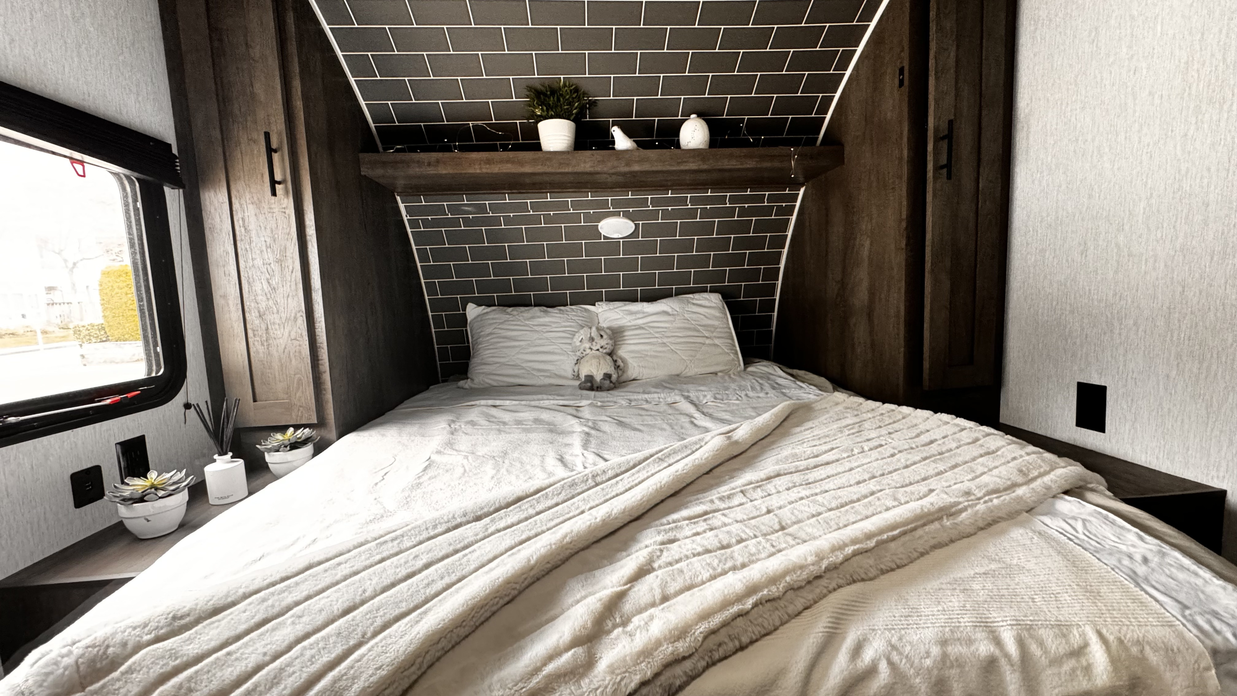 Inviting RV rental bedroom featuring a cozy bed with plush bedding, tiled headboard, and minimalist decor.. Forest River Salem 2022