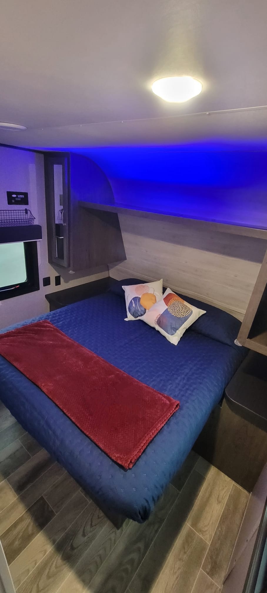 Bright and modern **rv rental** bedroom featuring a blue bed, red throw, and ambient blue lighting.. Jayco Jay Flight SLX 2021