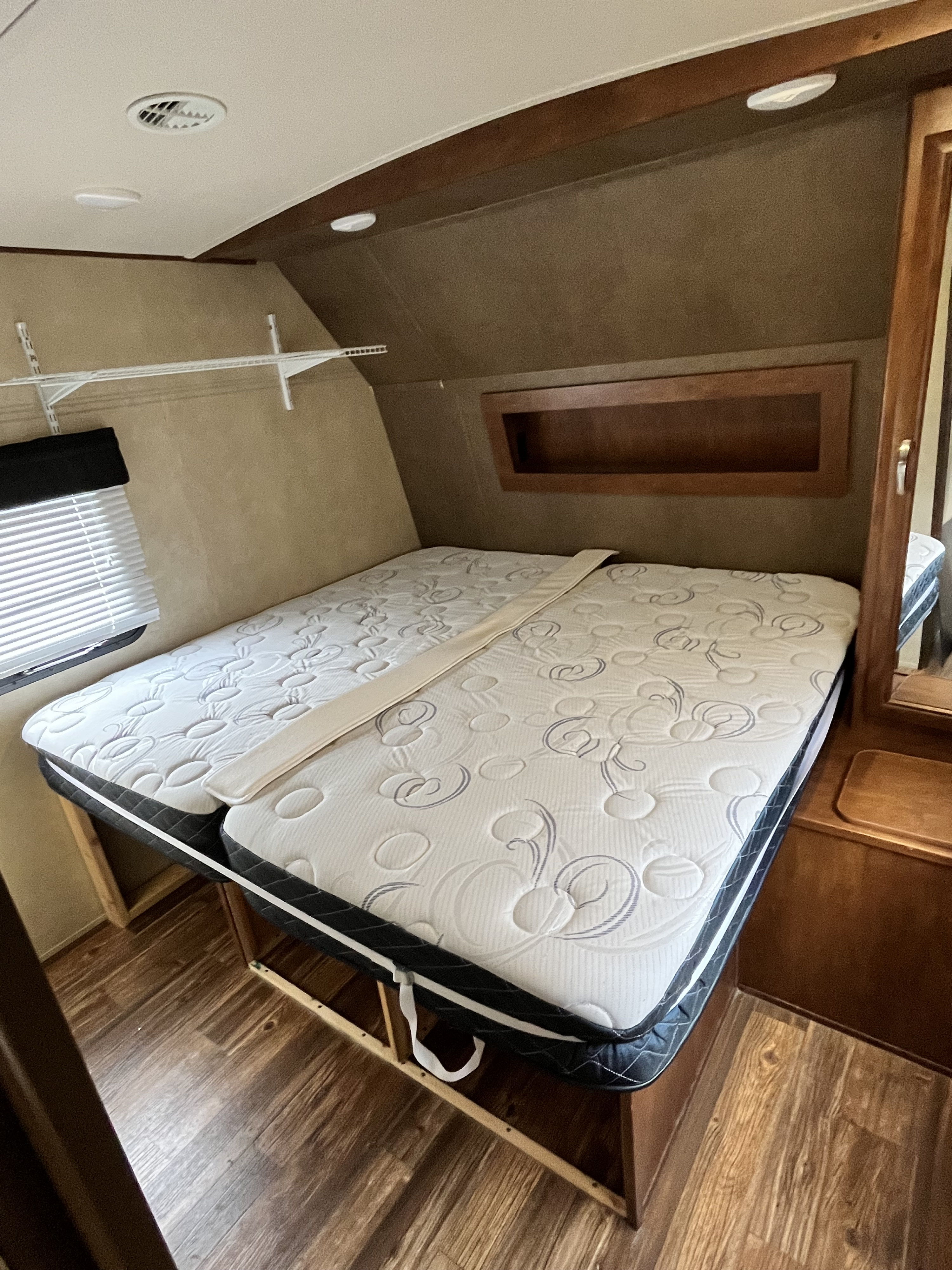 Cozy RV rental bedroom featuring a combined bed of two mattresses, window with blinds, shelf, and ceiling vents.. Forest River Vibe 2016