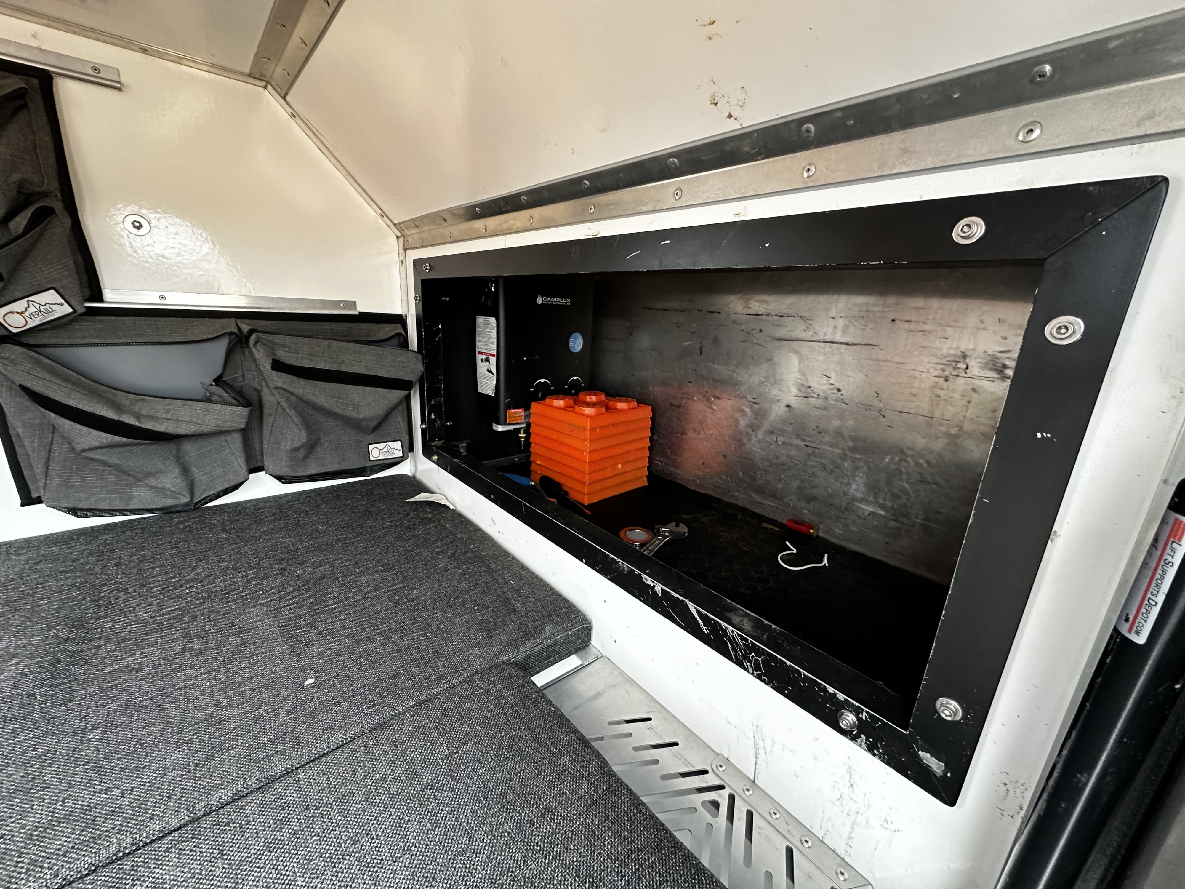 RV rental interior shows clever storage, cozy cushions, and essential Camplux water heater for comfortable travels.. Overkill Tk47 2020